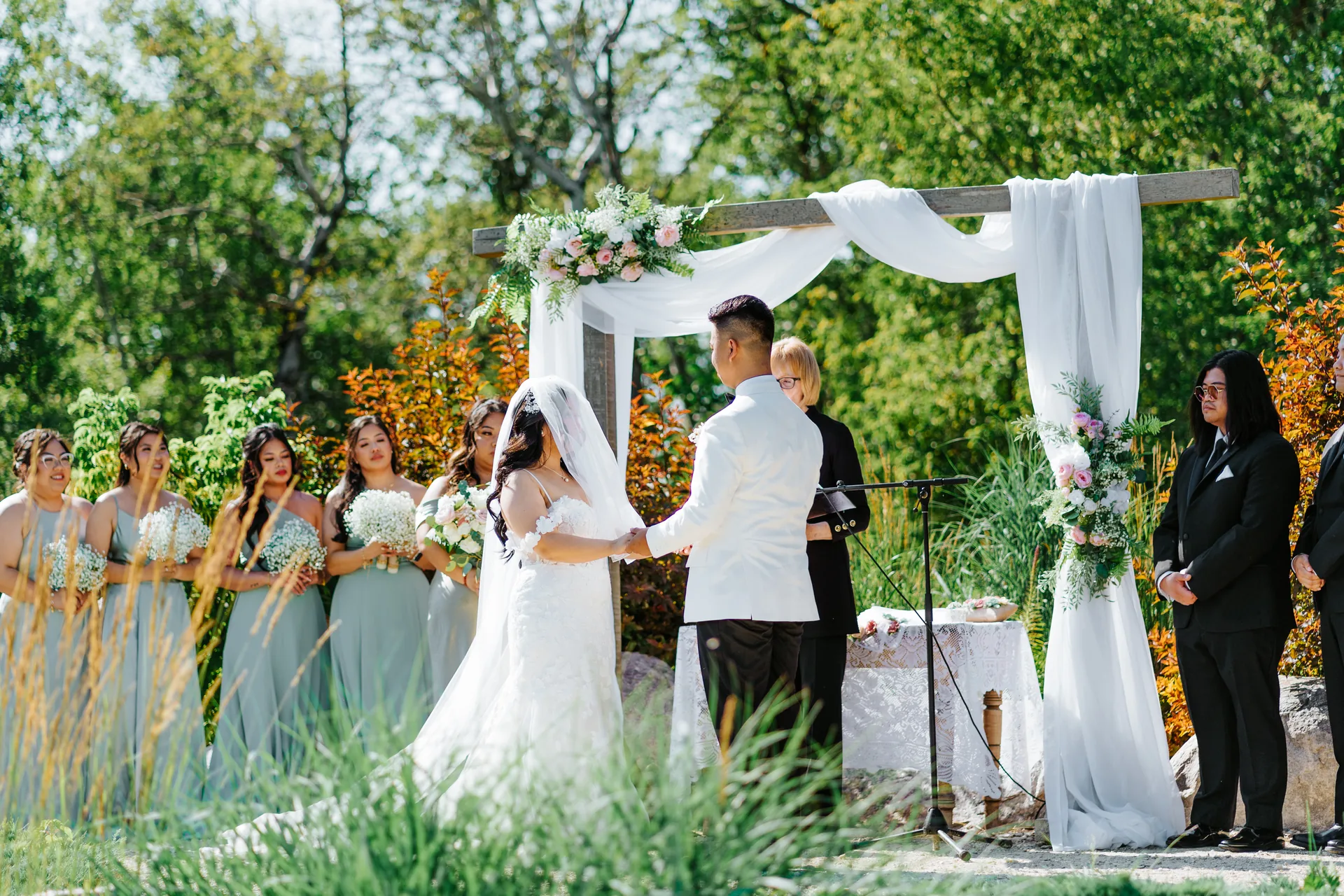 Wide ceremony shot showing Jay and Mark at the arbor with full bridal party at Hawthorne Estates, Manitoba