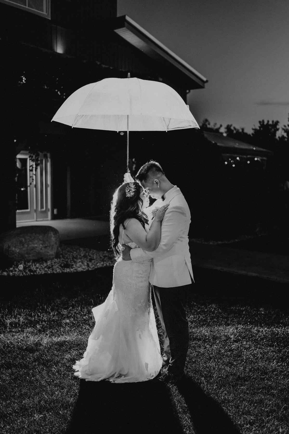 Jay and Mark embracing under an umbrella in the dark outside Hawthorne Estates, Manitoba