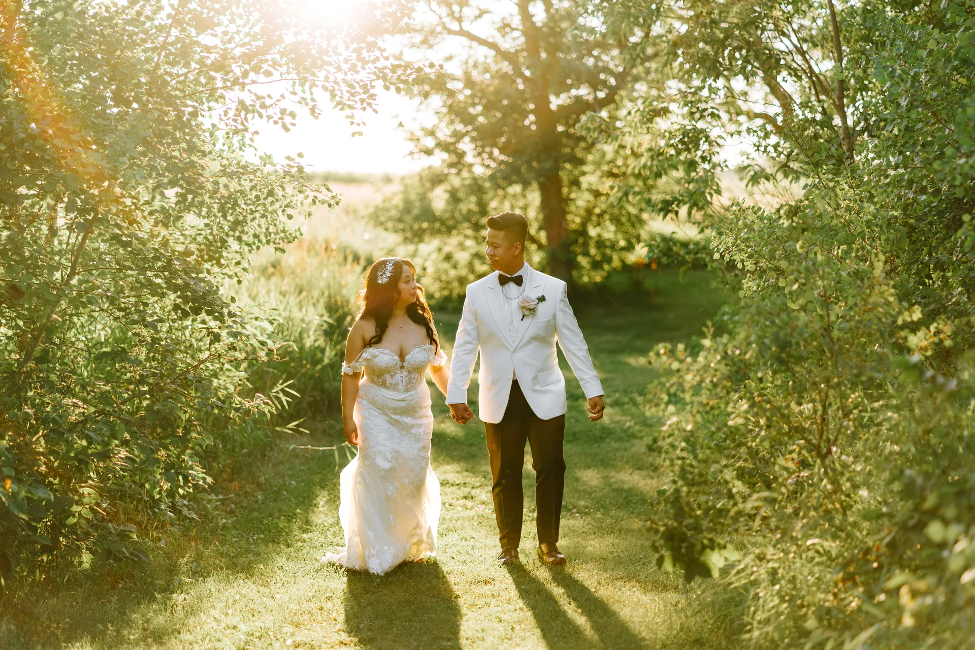 Jay and Mark walking a tree-lined path in golden hour light at Hawthorne Estates, Manitoba