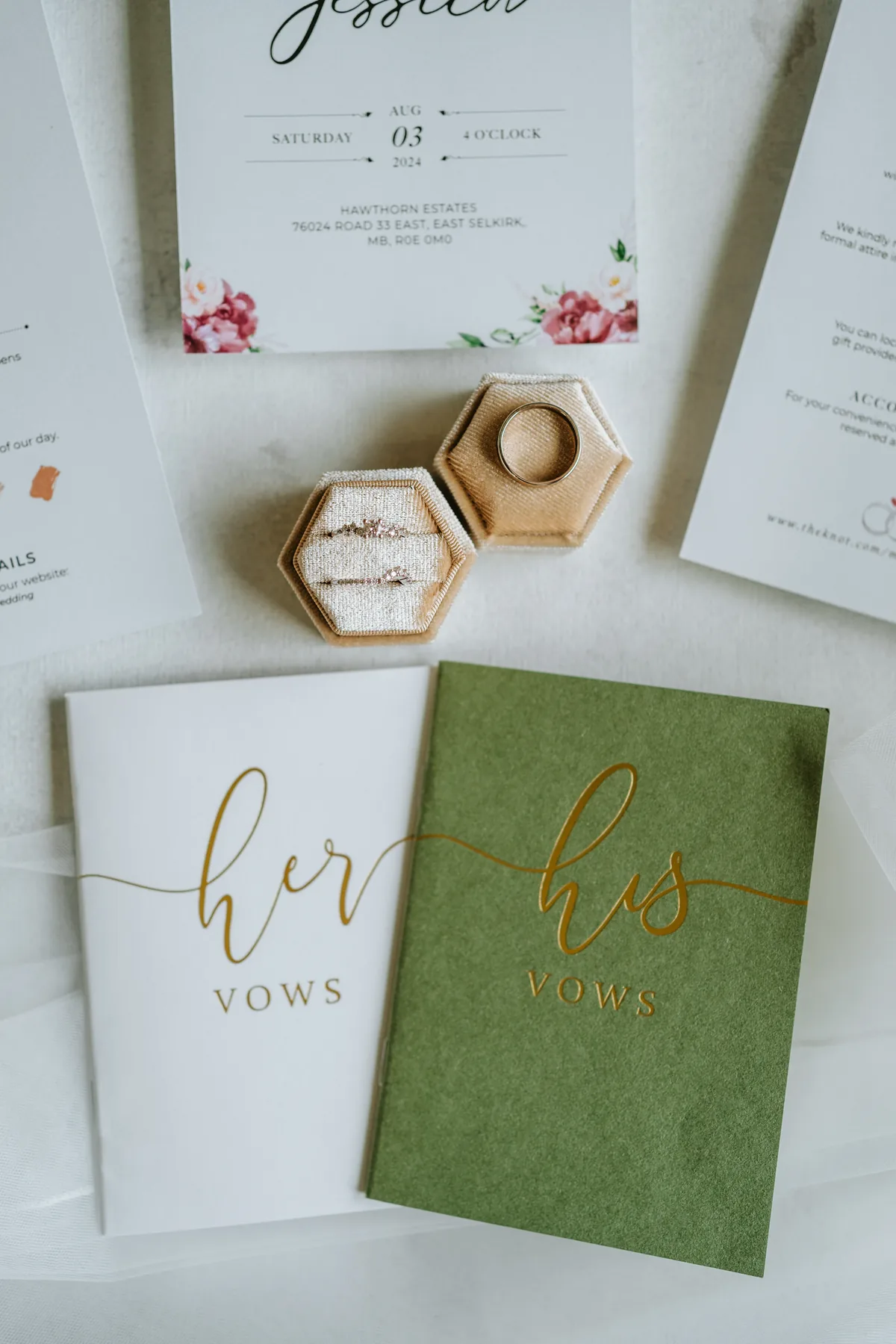 Wedding invitation, vow books, and rings flatlay detail — Jay and Mark's Hawthorne Estates wedding, Manitoba