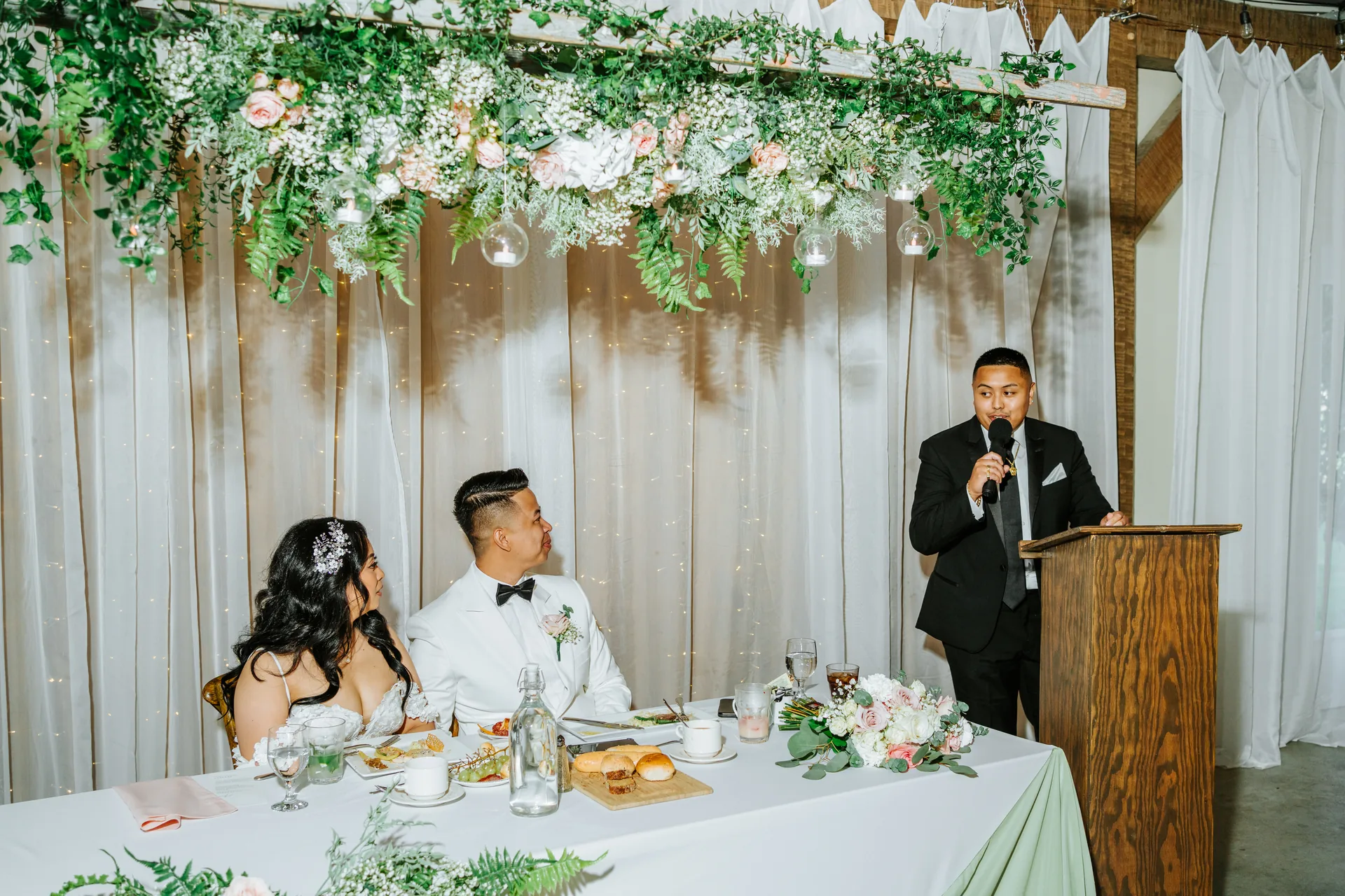 Speech at Jay and Mark's reception under the hanging greenery florals at Hawthorne Estates, Manitoba