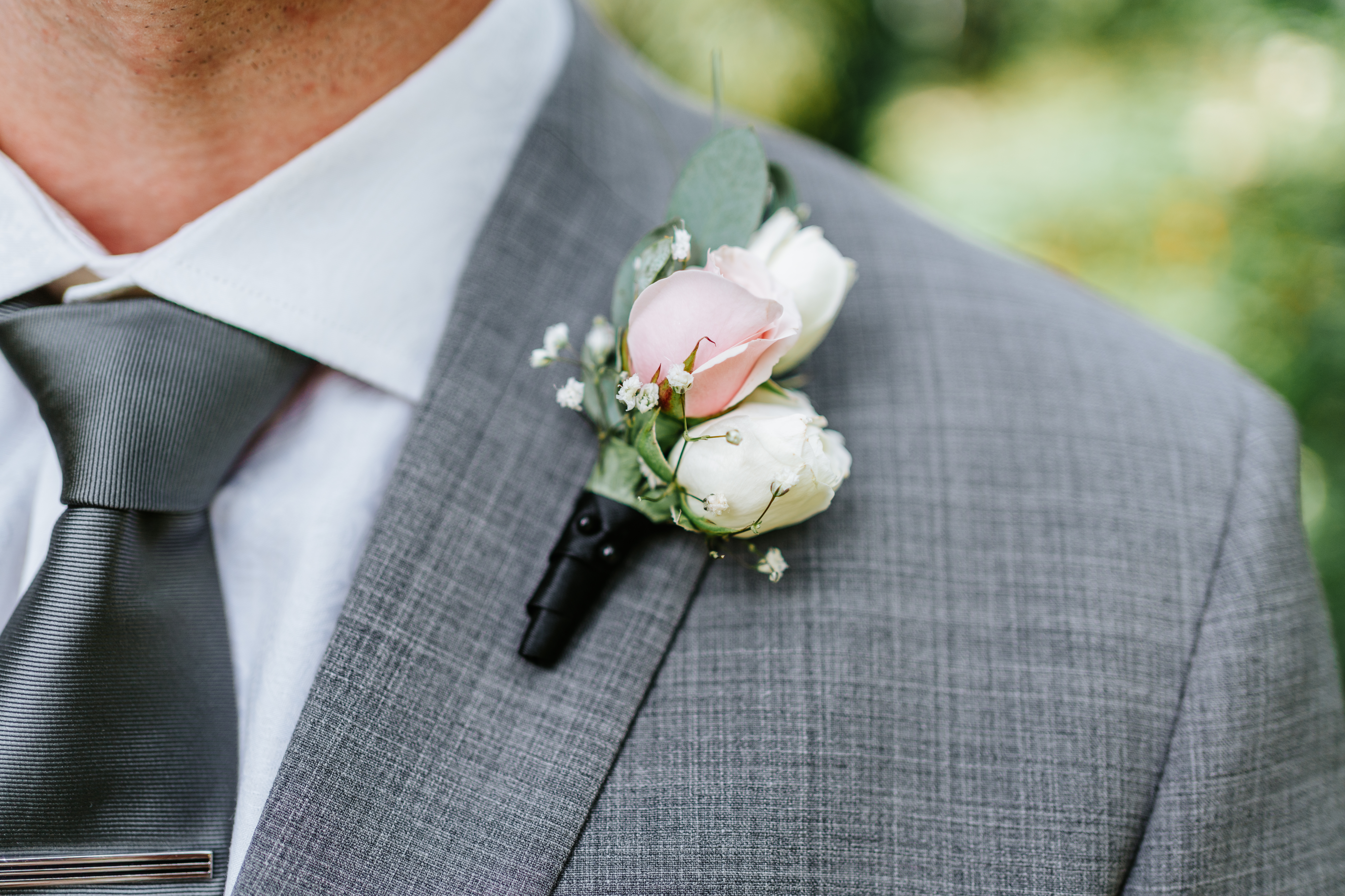 Pink rose and baby's breath boutonniere detail on Liam's gray suit — The Leaf Assiniboine Park wedding photography by Ngo Photography