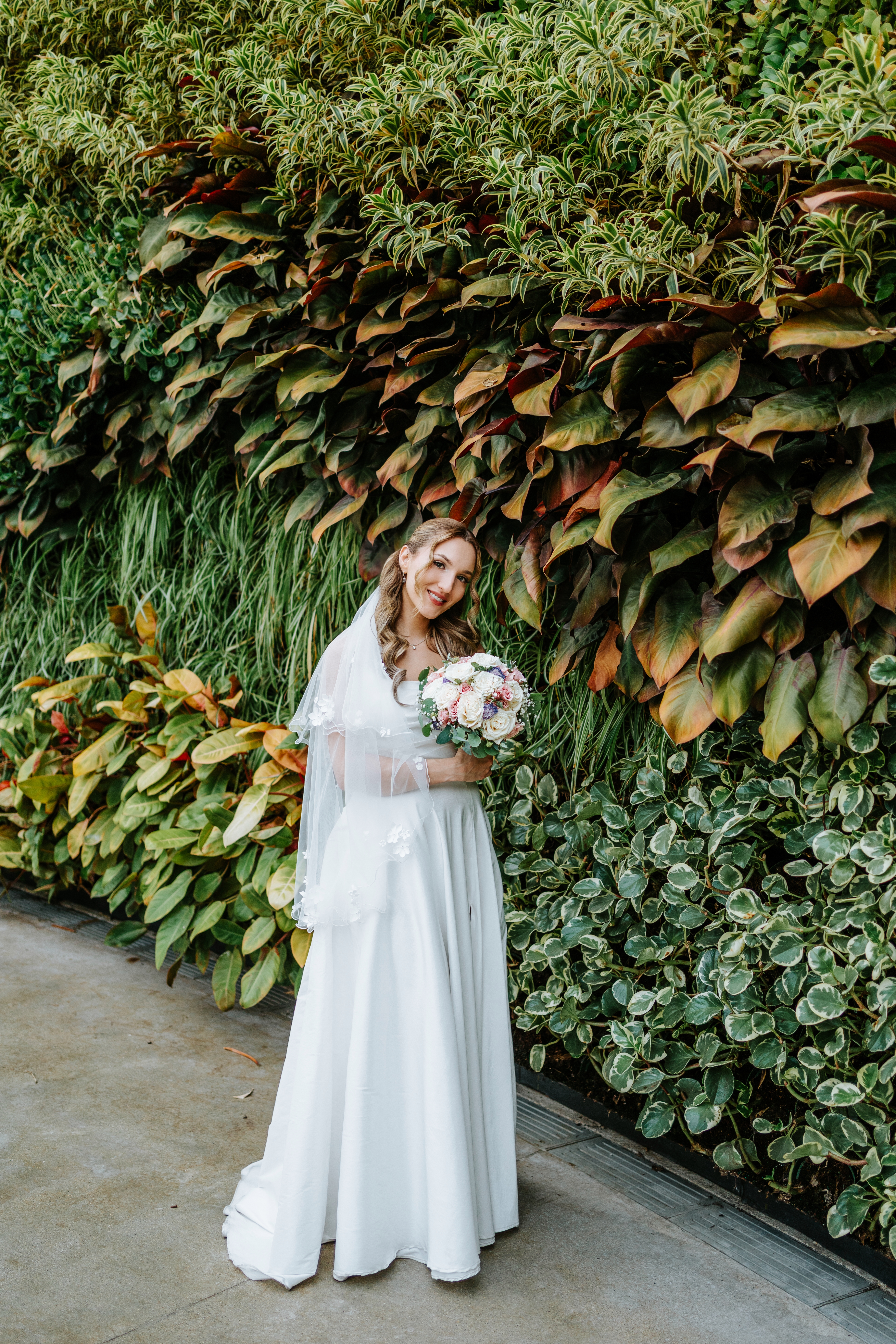 Bride portrait in front of The Leaf's dramatic living plant wall at Assiniboine Park Winnipeg — wedding photography by Chris Ngo