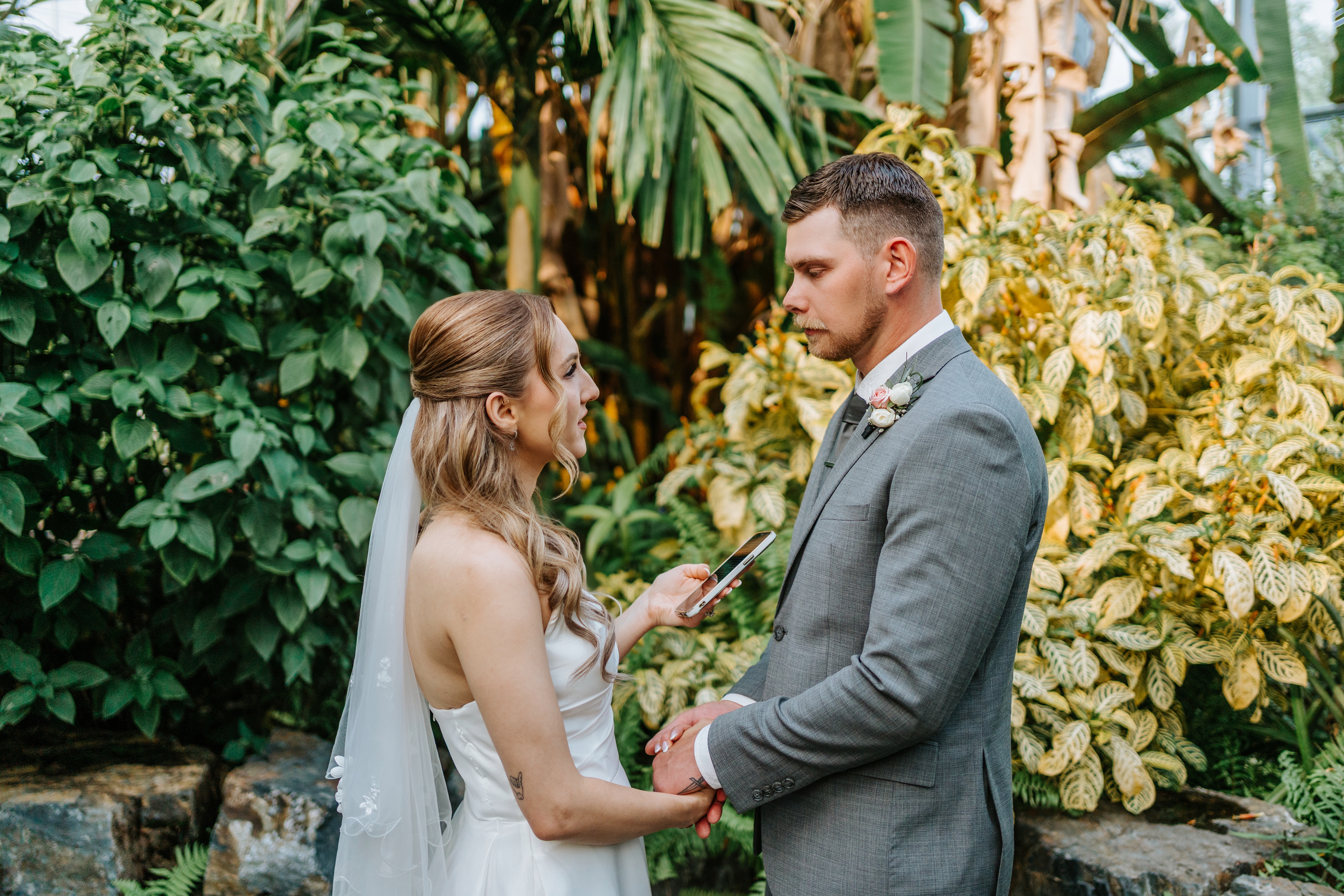 Tanya reading her vows during the intimate wedding ceremony inside The Leaf Assiniboine Park surrounded by colorful tropical plants — wedding photography by Chris Ngo Winnipeg