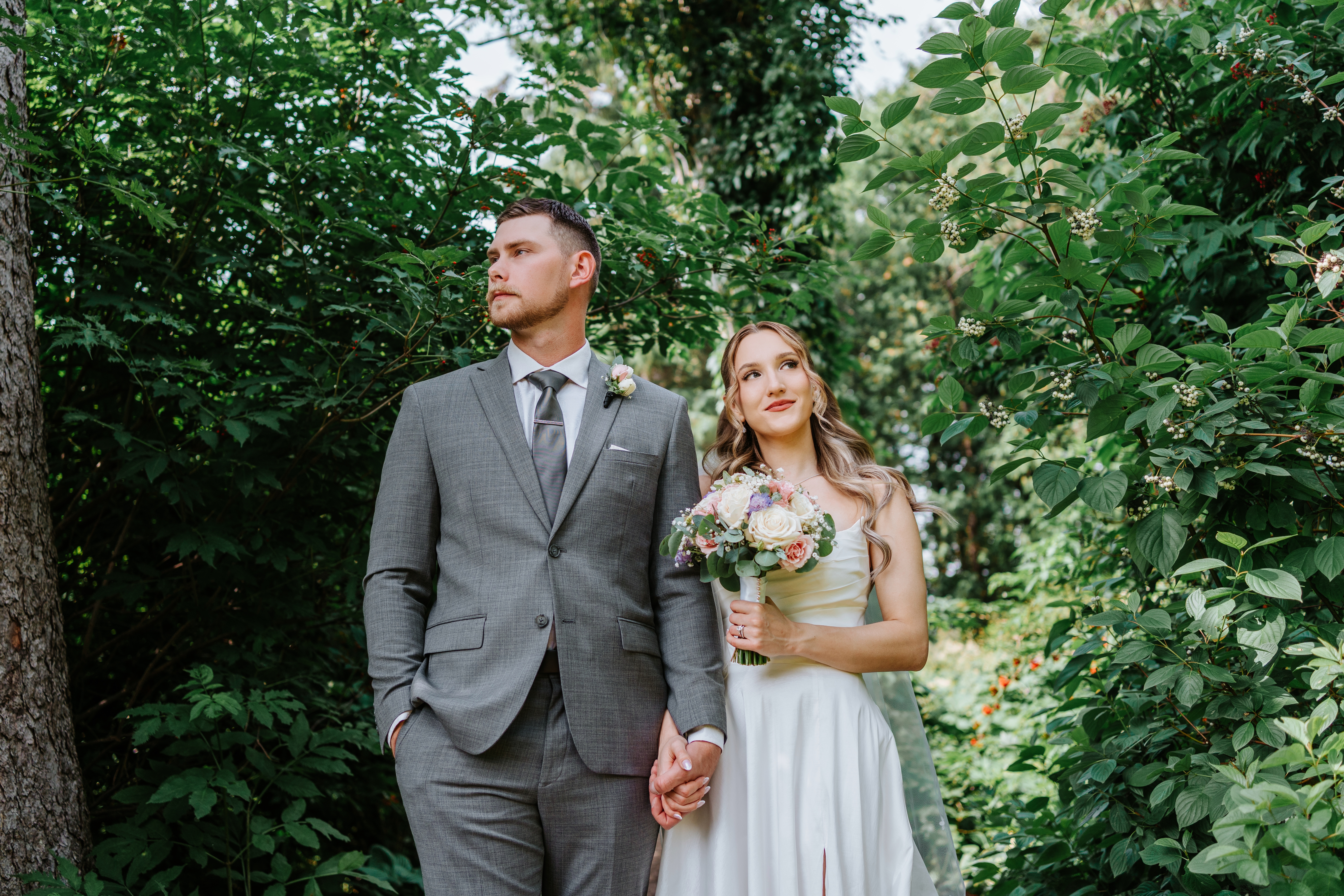 Liam and Tanya looking up through berry-laden branches at Assiniboine Park — intimate wedding photography by Chris Ngo Winnipeg