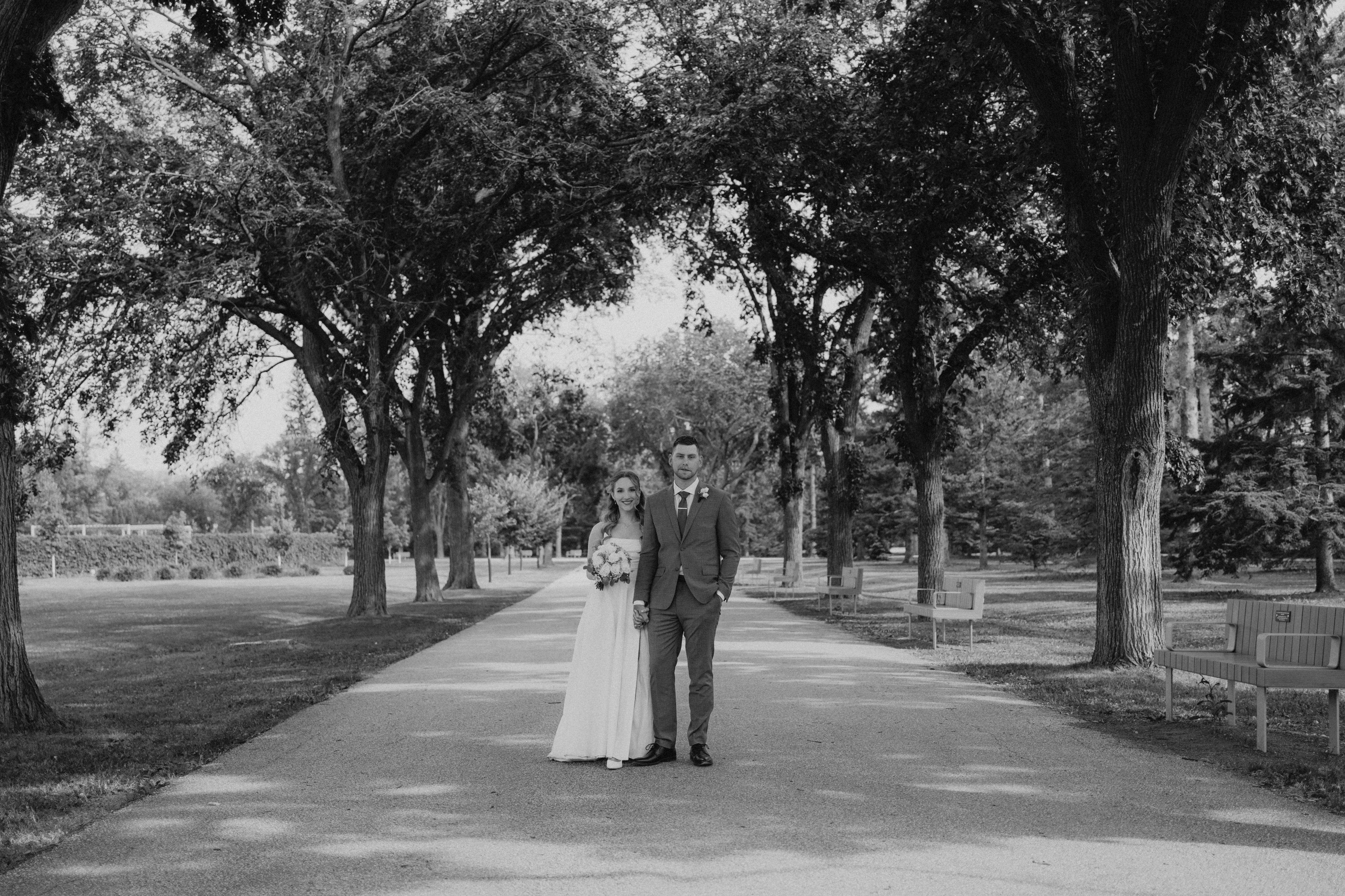 Liam and Tanya on the classic tree-lined promenade at Assiniboine Park after their ceremony at The Leaf Winnipeg — Ngo Photography