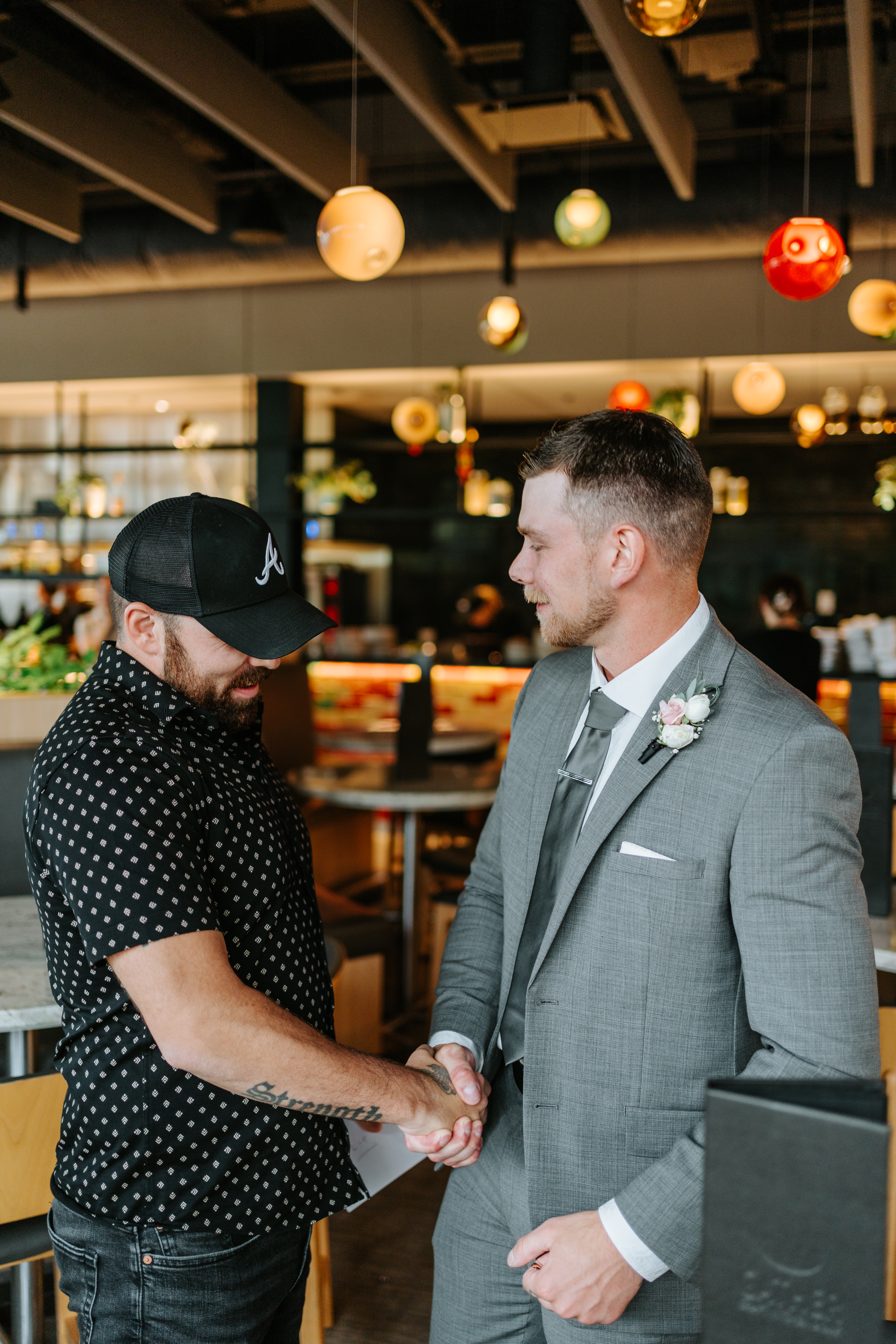 Liam inside The Leaf at Assiniboine Park with colourful pendant lights and tropical plants in the background — wedding photography by Ngo Photography Winnipeg