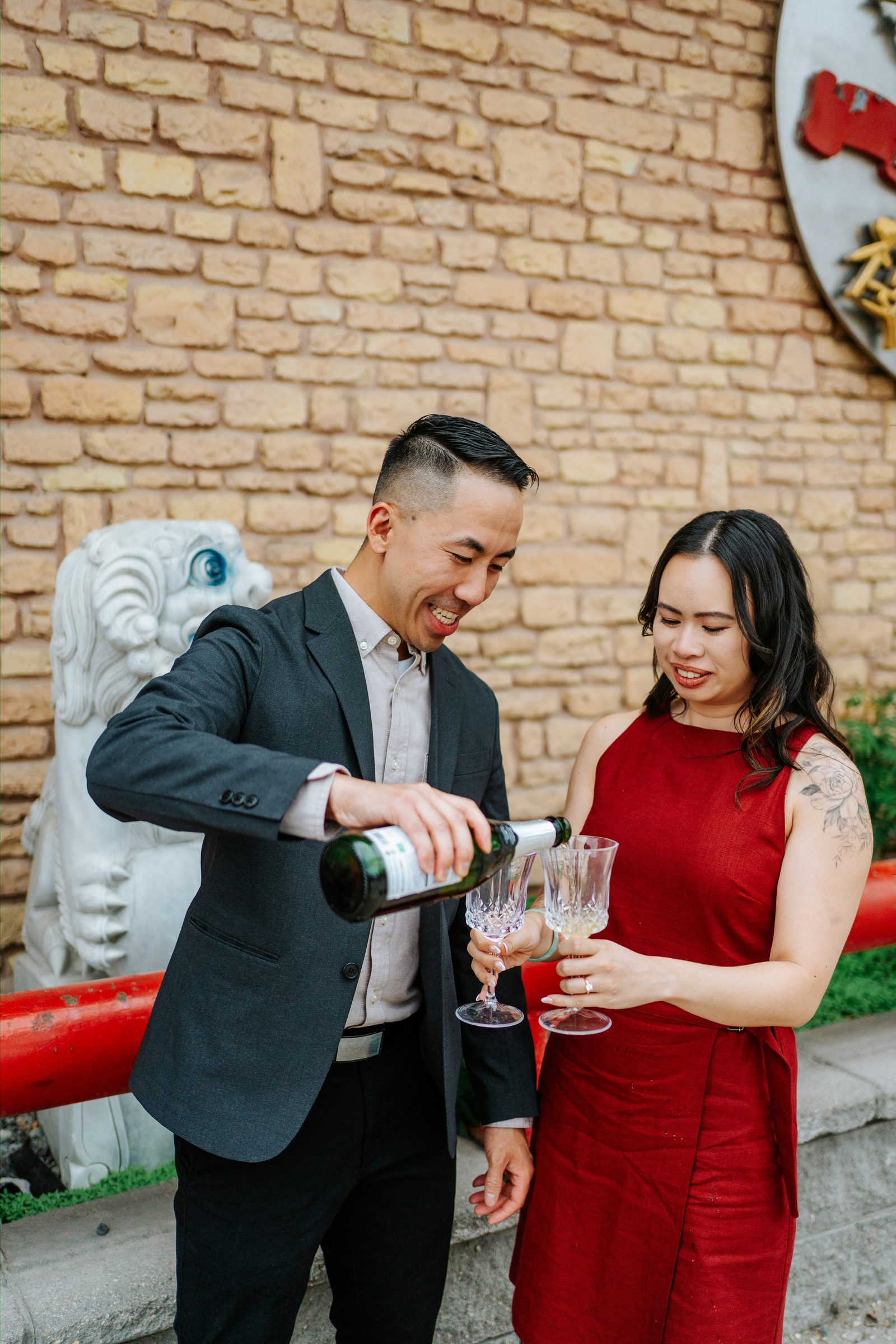 Monica and Jason candid portrait against the brick exterior of Kum Koon Garden — Winnipeg Chinese restaurant engagement by Ngo Photography