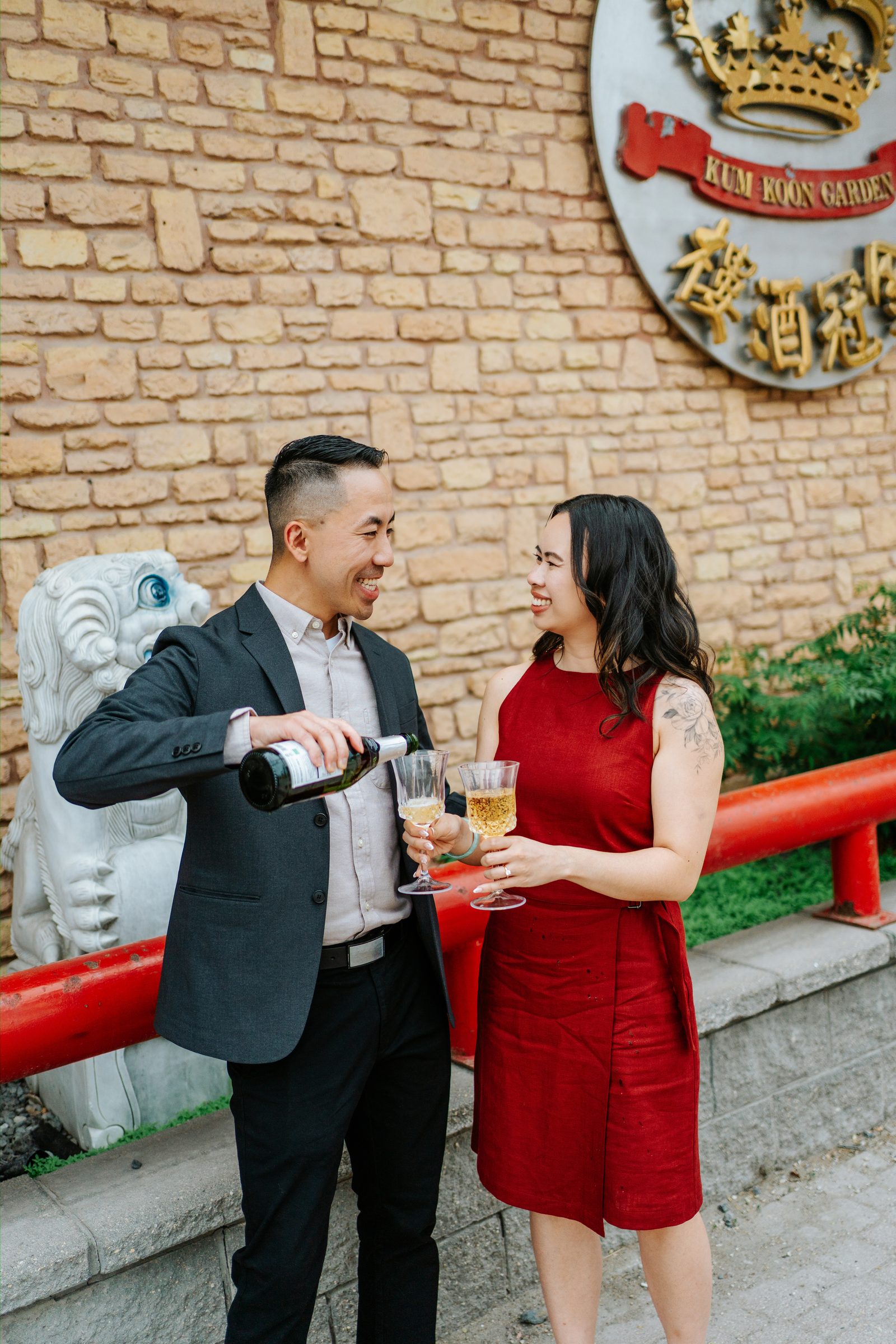Jason and Monica laughing outside Kum Koon Garden restaurant with stone lion guardian — Winnipeg Chinese heritage engagement photography by Ngo Photography
