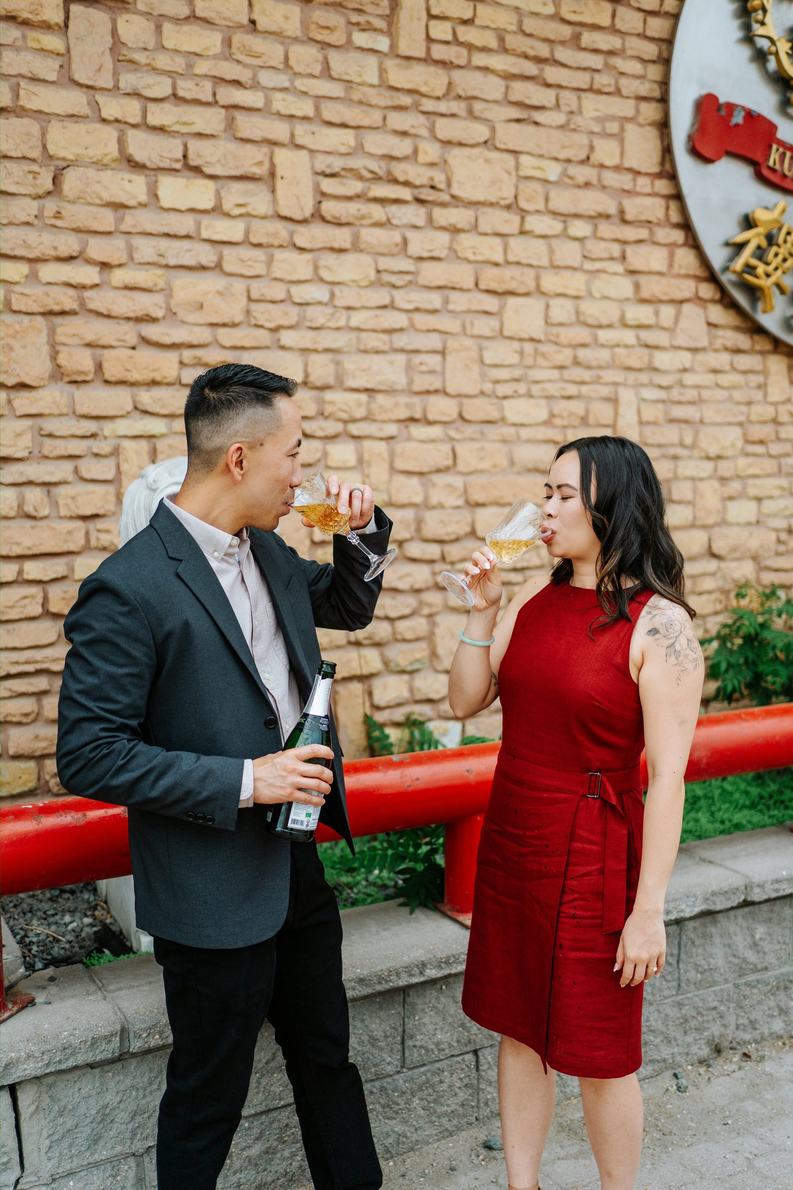 Monica and Jason portrait against the brick wall of Kum Koon Garden — Winnipeg Chinatown engagement photography by Ngo Photography