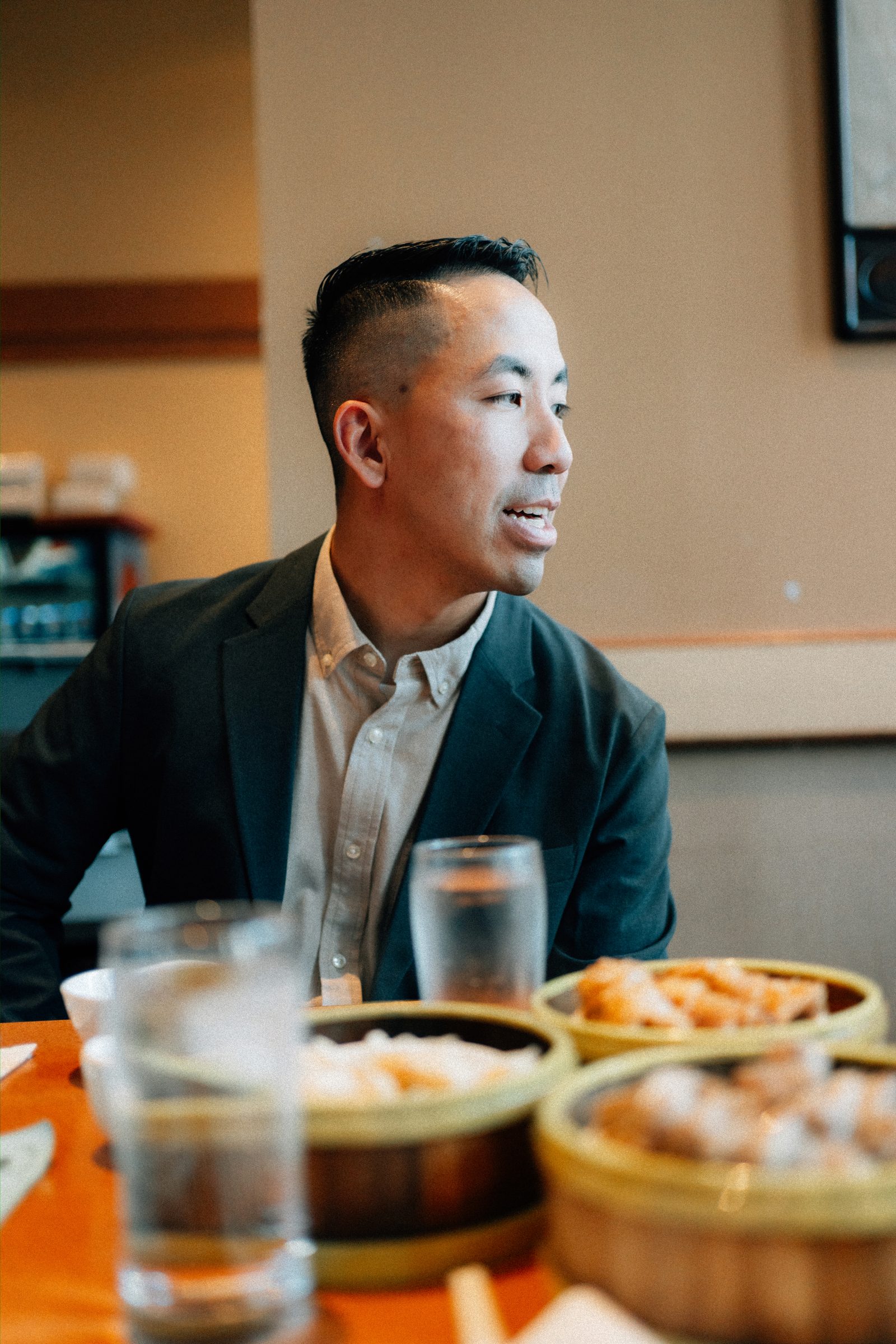 Monica and Jason seated at a round table at Kum Koon Garden Winnipeg with red lanterns — Chinese restaurant engagement photography by Ngo Photography