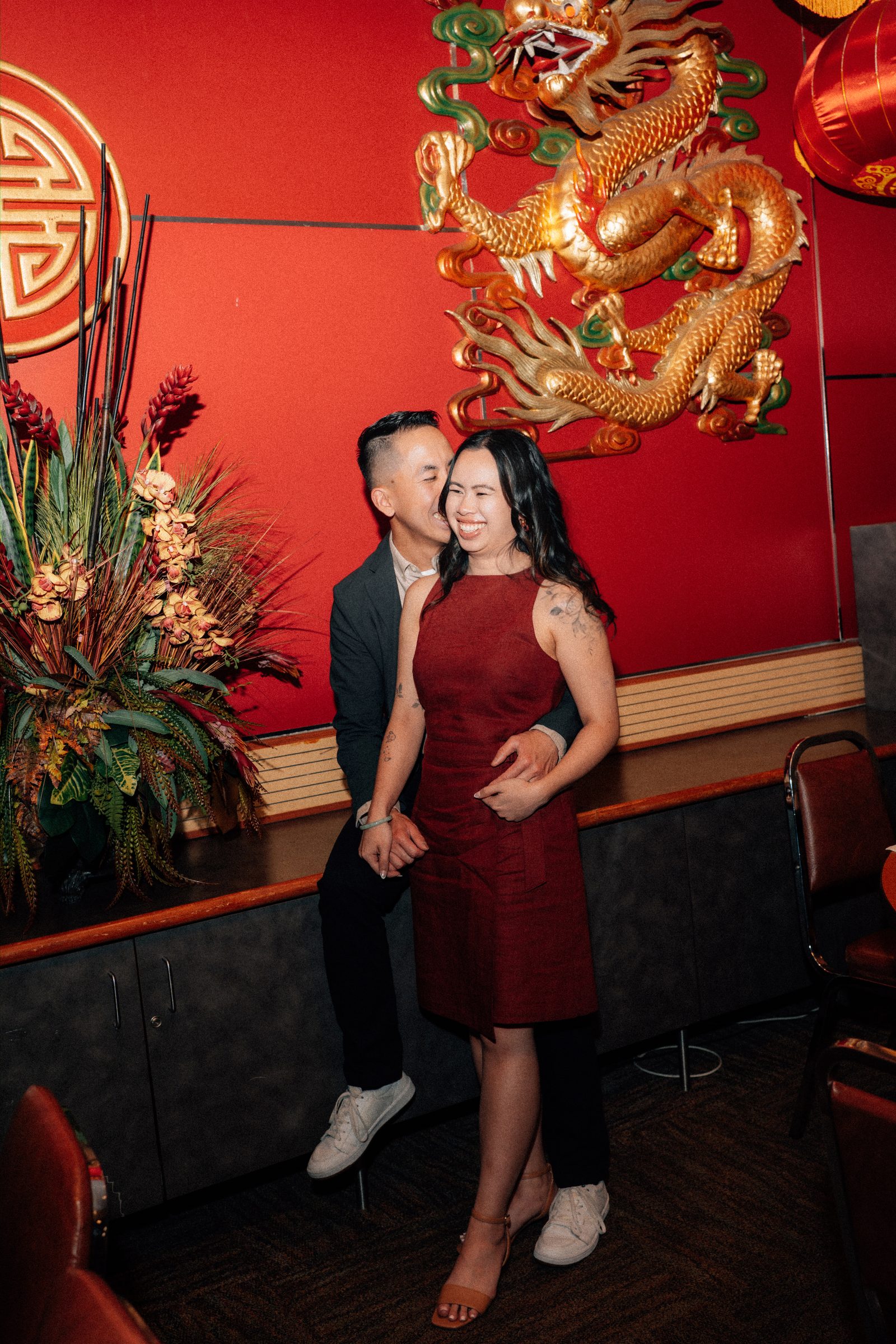 Wide shot of Monica and Jason inside Kum Koon Garden with traditional Chinese restaurant interior and red lanterns — Winnipeg engagement photography by Ngo Photography