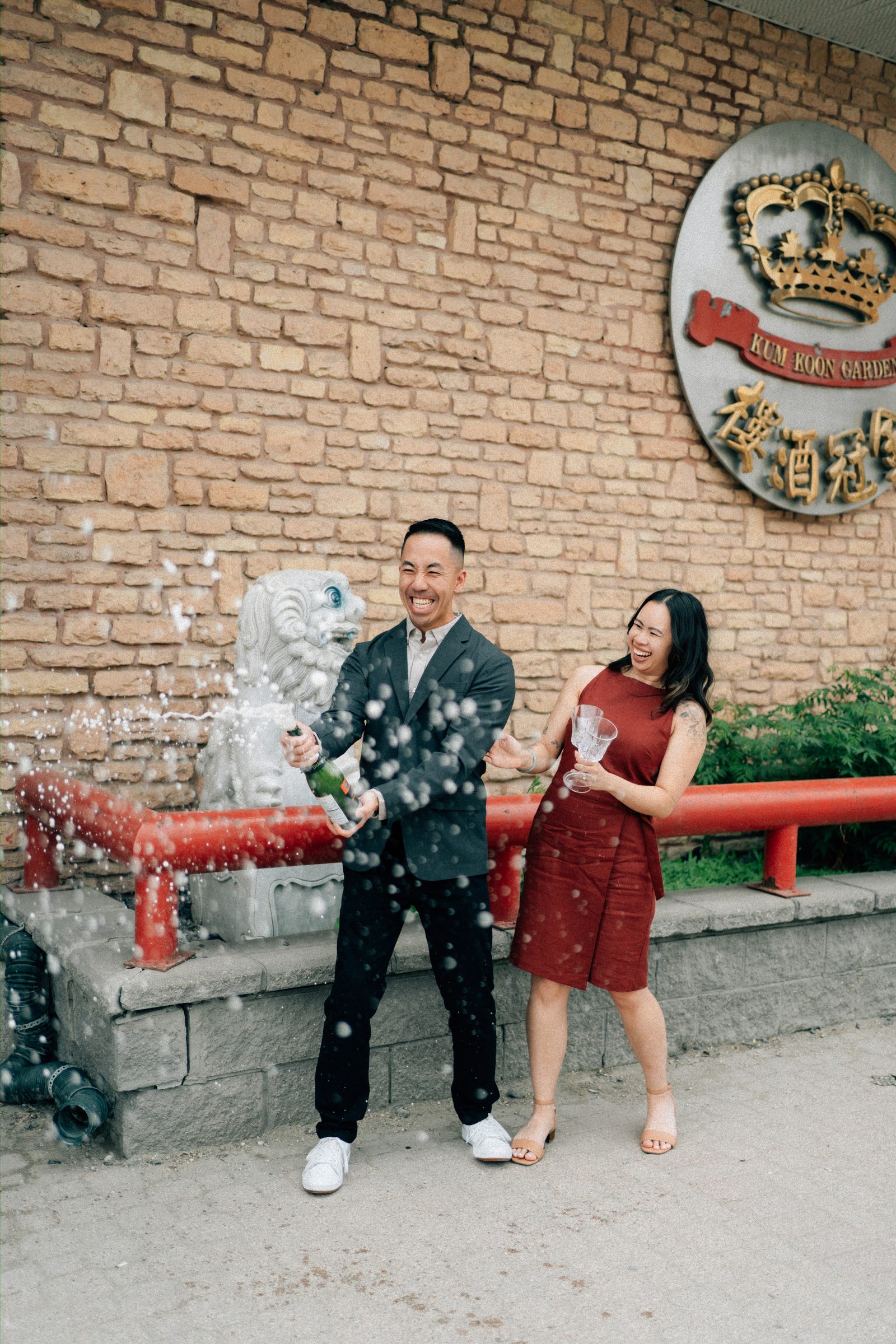 Monica in red dress and Jason in blazer at Kum Koon Garden Winnipeg — Chinese restaurant engagement photography by Ngo Photography