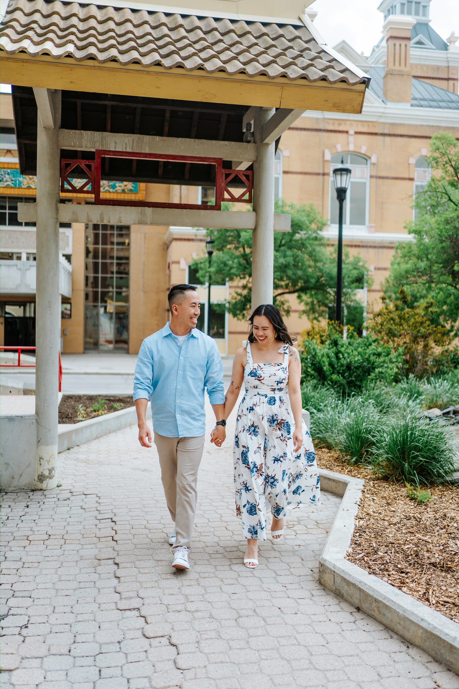 Monica and Jason walking hand in hand through the pagoda walkway in Winnipeg Chinatown — Chinese Vietnamese engagement photography by Chris Ngo, Ngo Photography