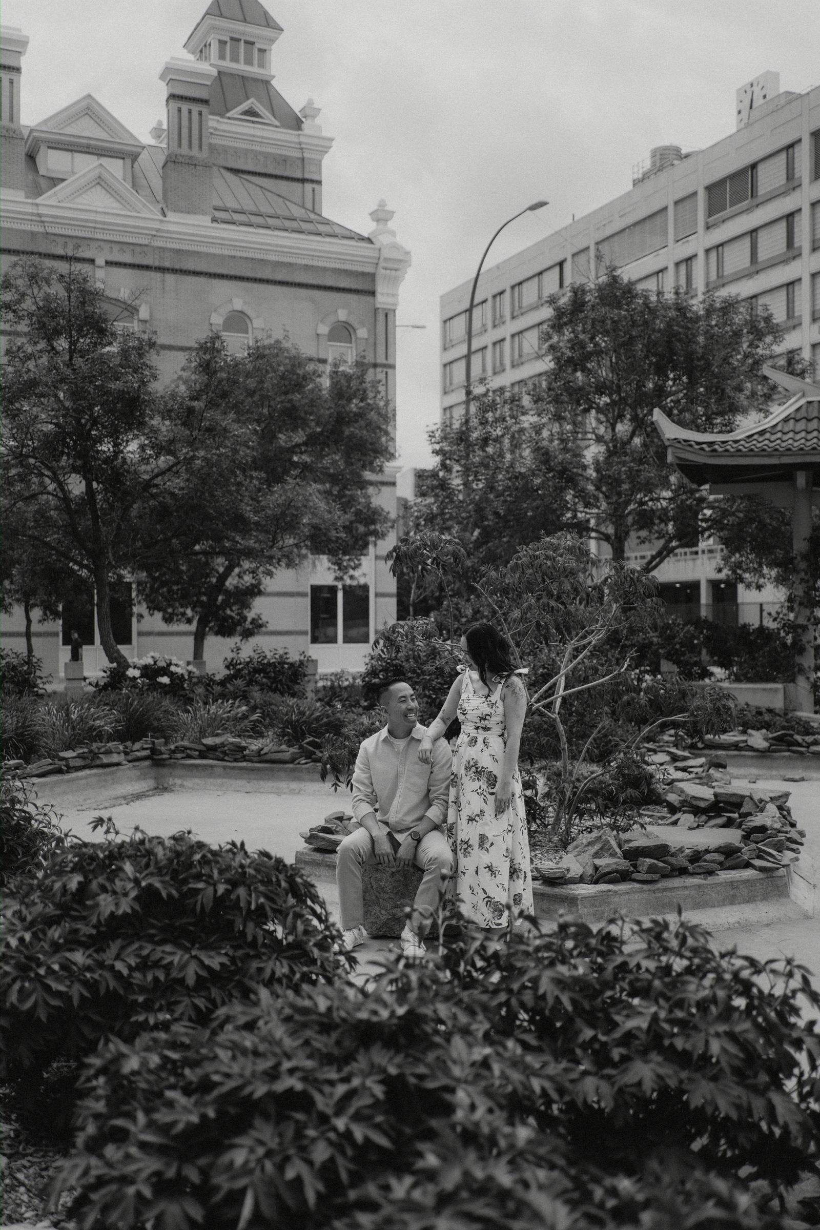 Jason holding Monica close in the pagoda walkway in Winnipeg Chinatown — engagement photography by Chris Ngo