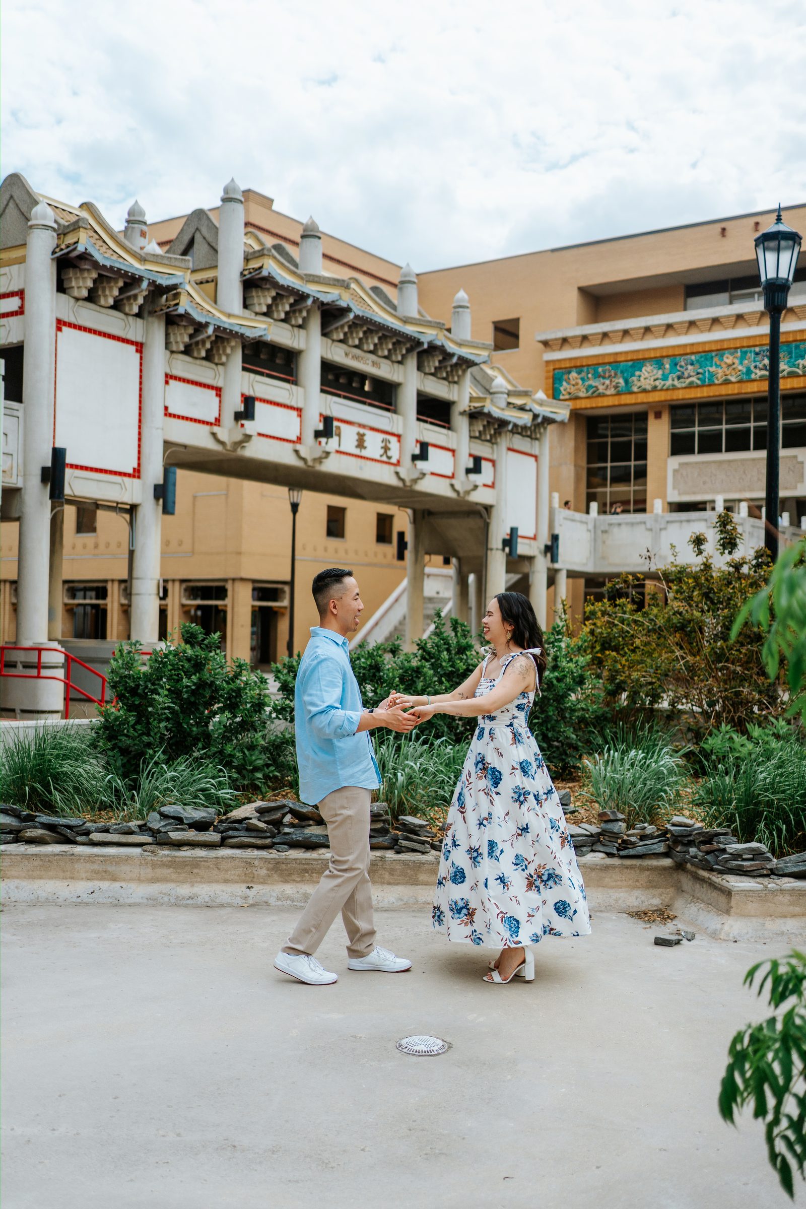 Monica and Jason walking past the Chinese Cultural Centre in Winnipeg Chinatown — engagement photography by Ngo Photography