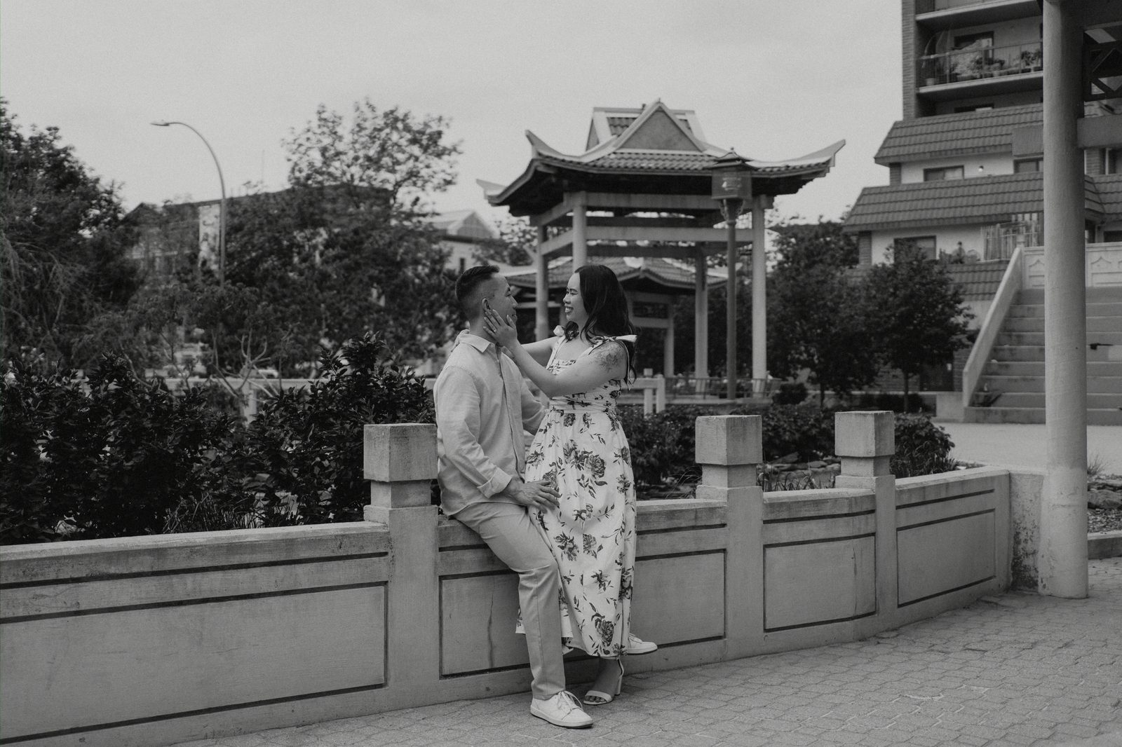 Monica and Jason walking hand in hand past Chinatown storefronts in Winnipeg — engagement photography by Ngo Photography