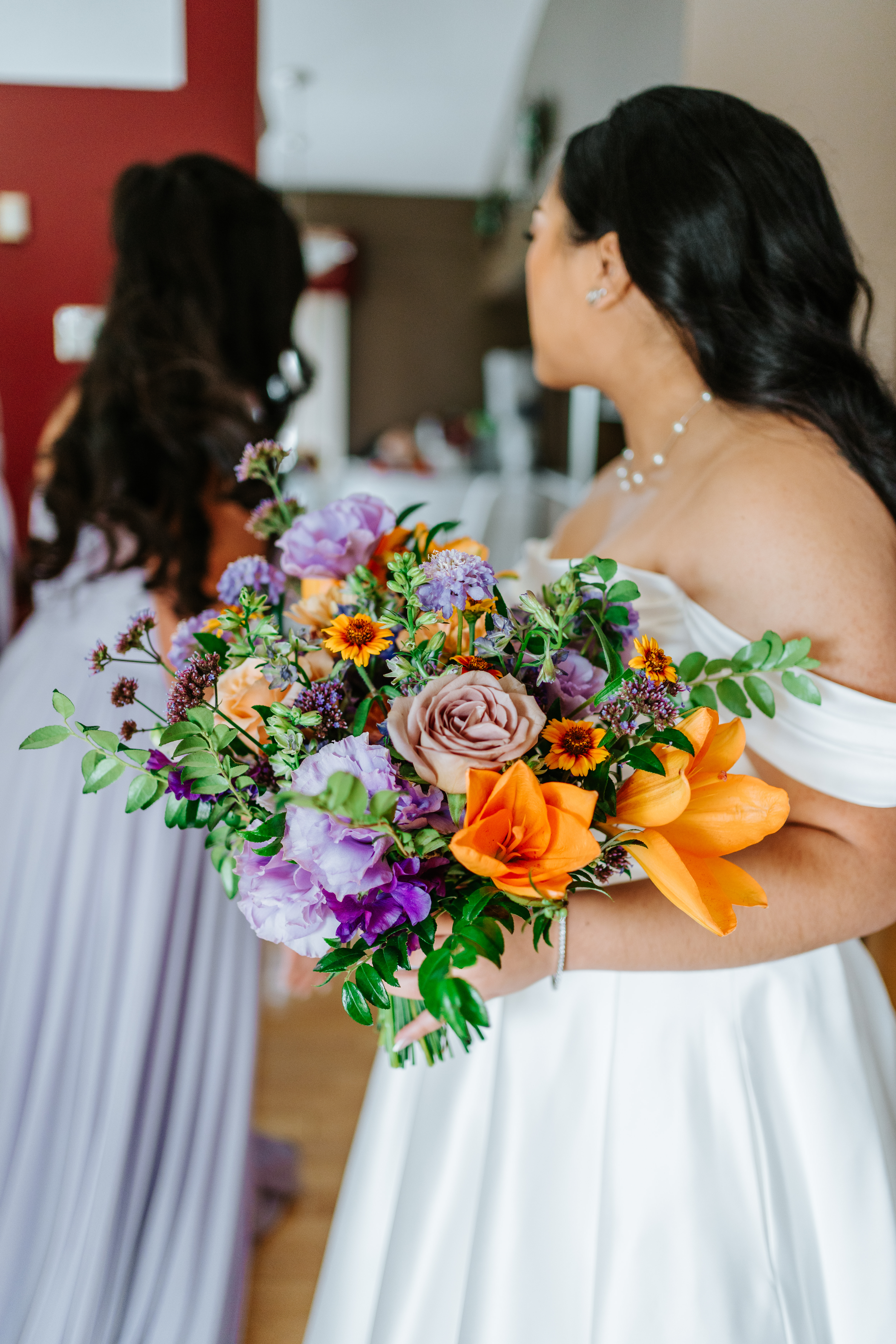 Ayanna in her off-shoulder ballgown holding the colourful orange and purple bridal bouquet from behind — getting ready photography by Ngo Photography