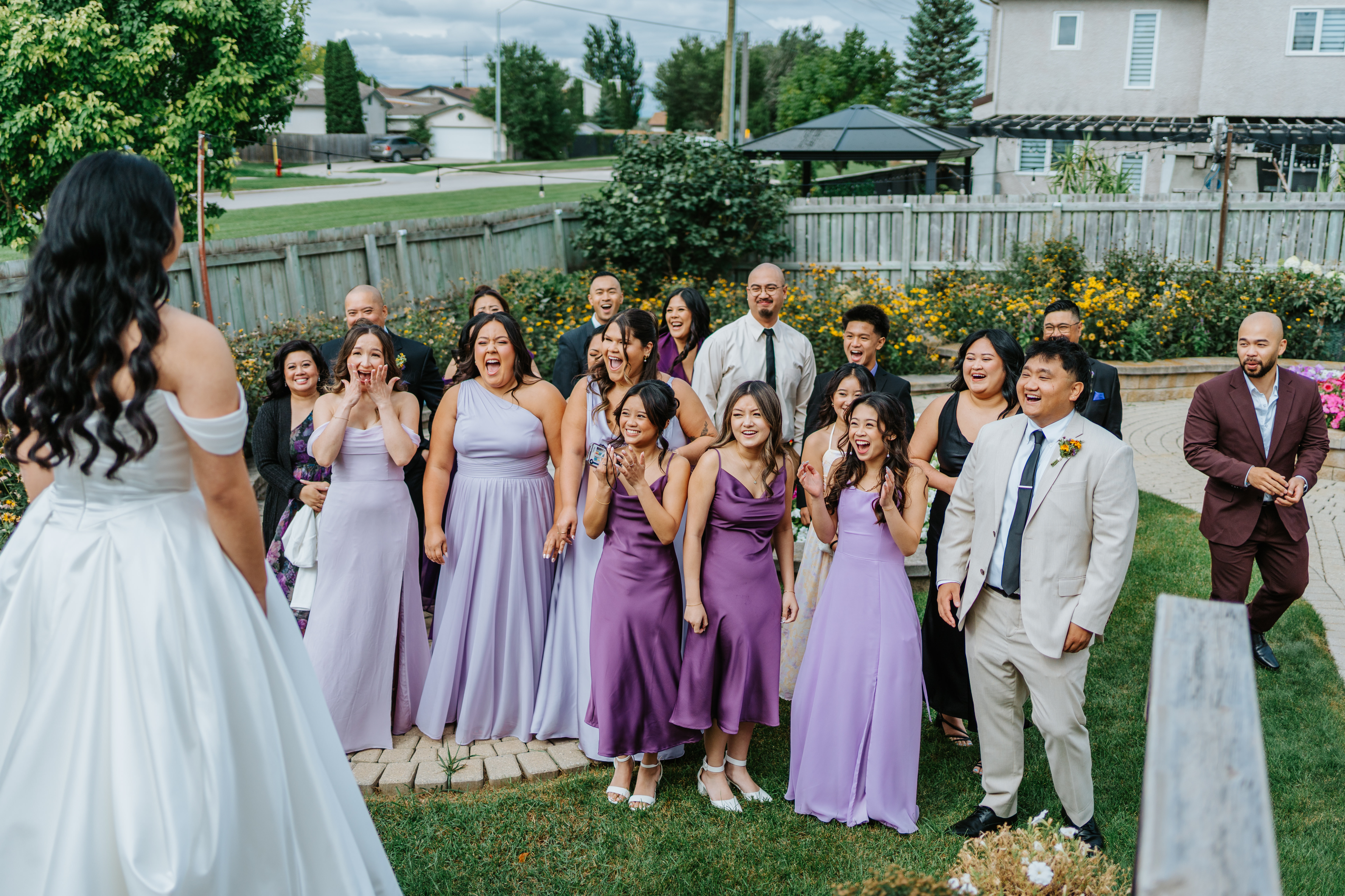 Friends and family react with open mouths and pure joy as Ayanna steps out in her wedding gown — bride reveal photography by Ngo Photography Winnipeg