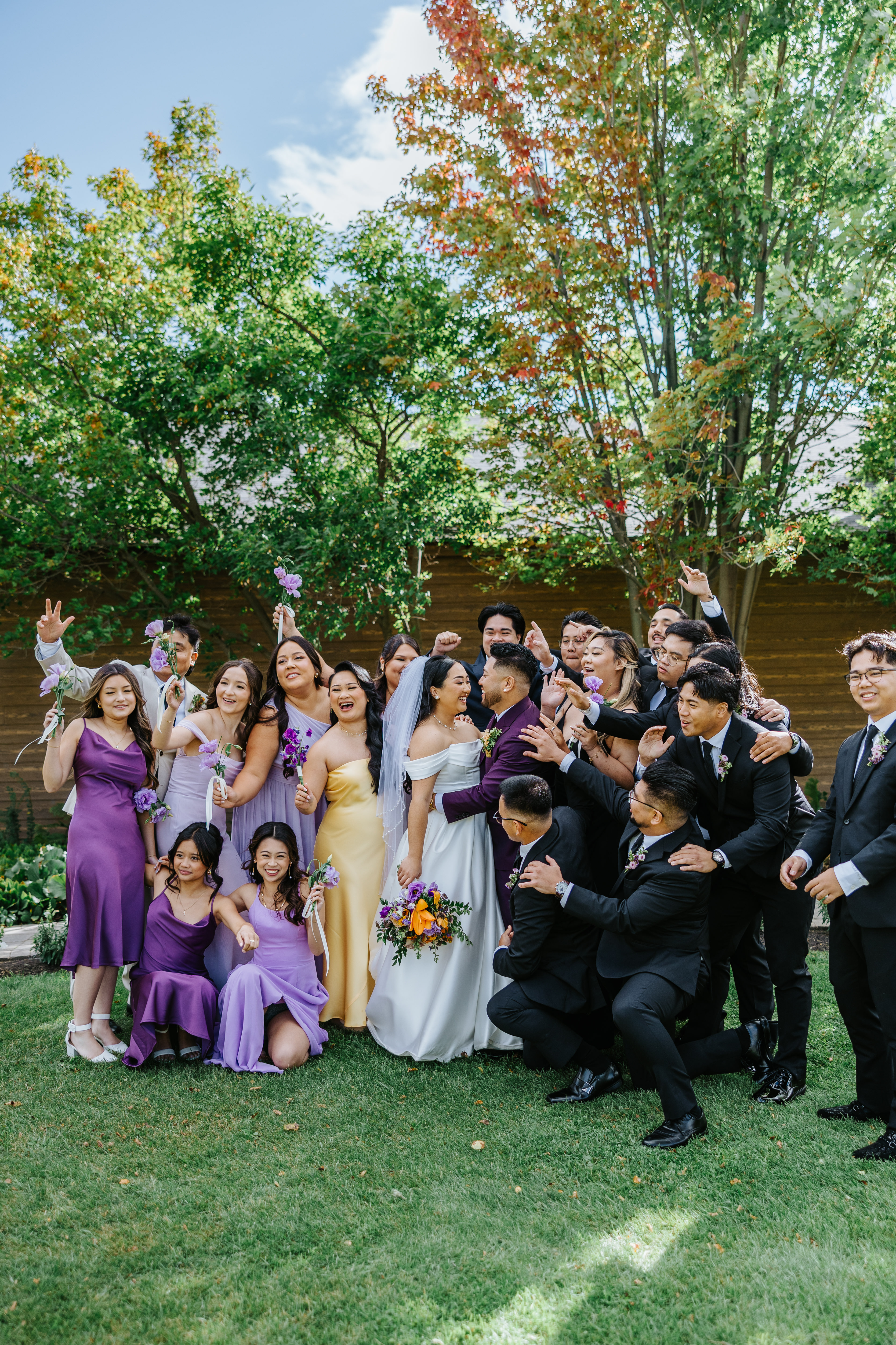 Full wedding party celebrating together in the garden at Breezy Bend Country Club Winnipeg — wedding photography by Ngo Photography