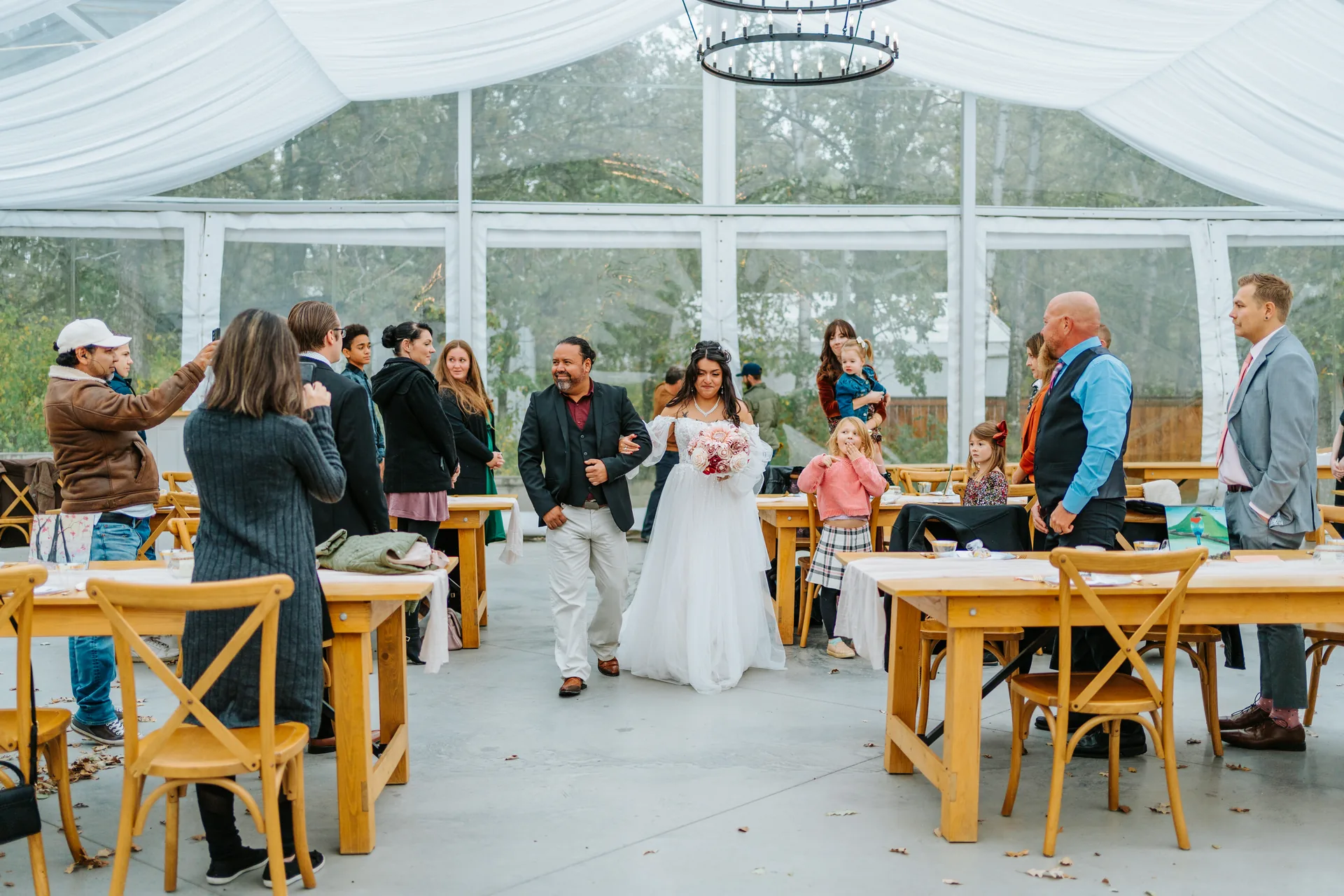 Ceremony inside the glass marquee tent at Oakland Estates Manitoba — wooden arch dressed with fall florals and blush flowers