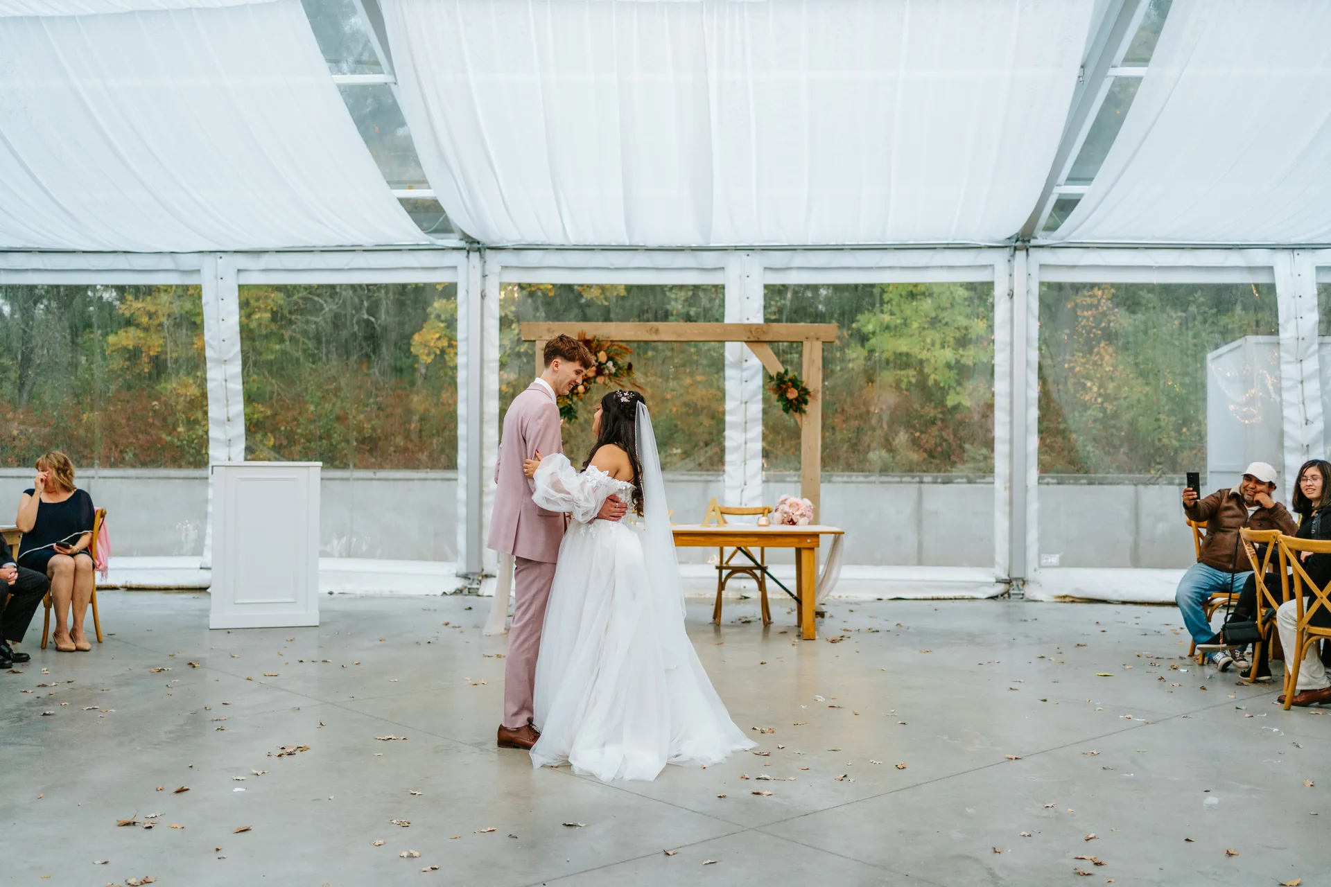 Paola and Riley first dance under the wooden arch inside the glass tent at Oakland Estates Manitoba wedding by Chris Ngo