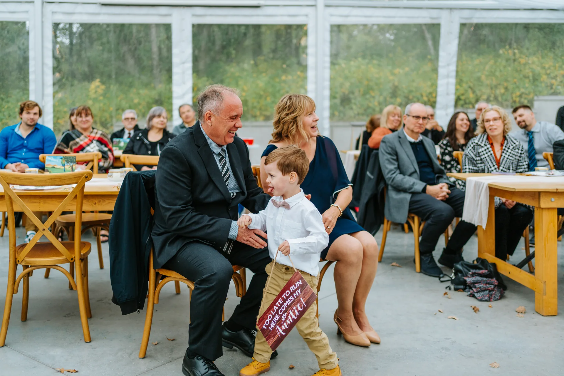 Ring bearer with sign walking the processional aisle at Oakland Estates Manitoba wedding ceremony — Ngo Photography