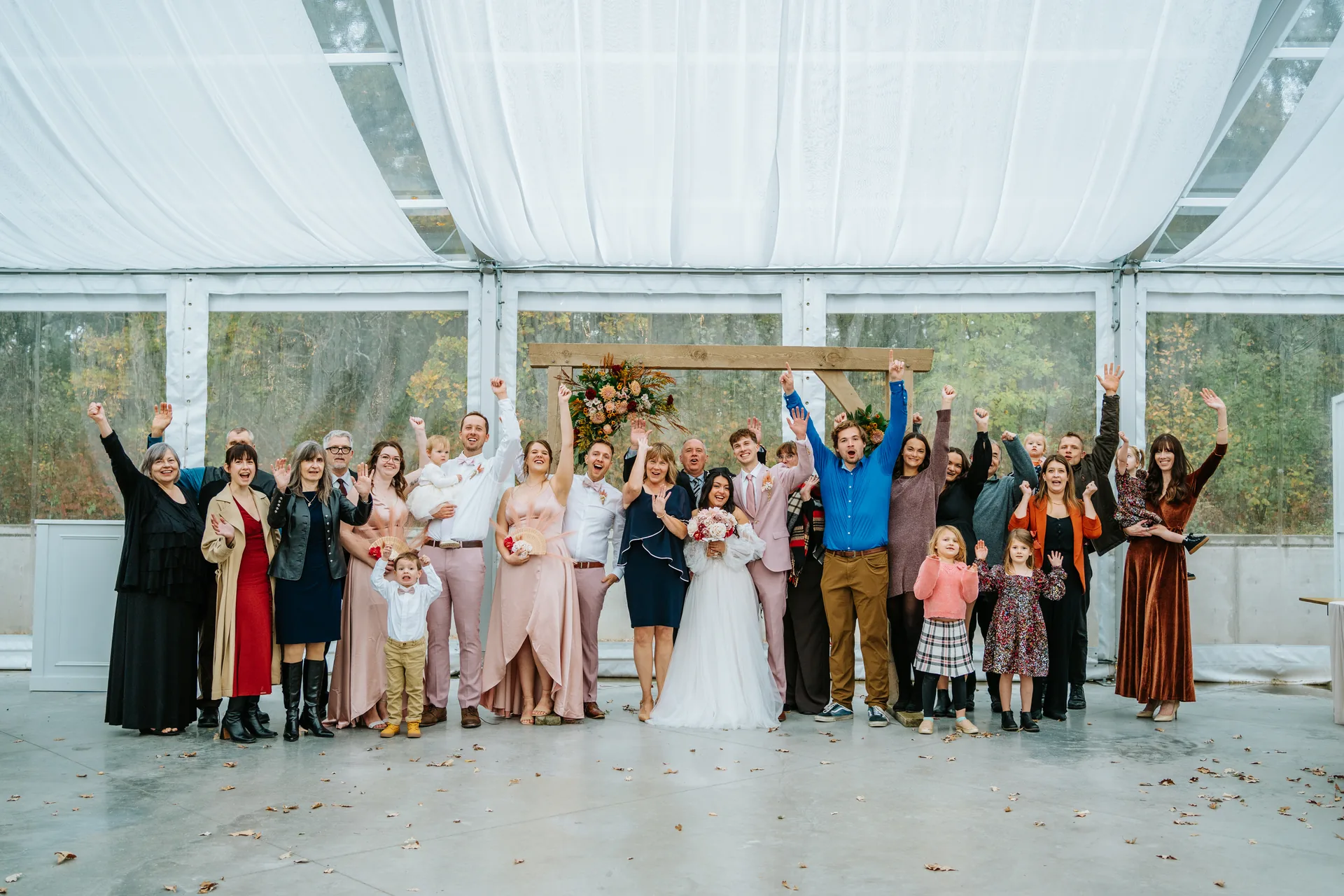 Wedding party portrait outside the glass tent at Oakland Estates Manitoba — blush bridesmaid dresses and suits