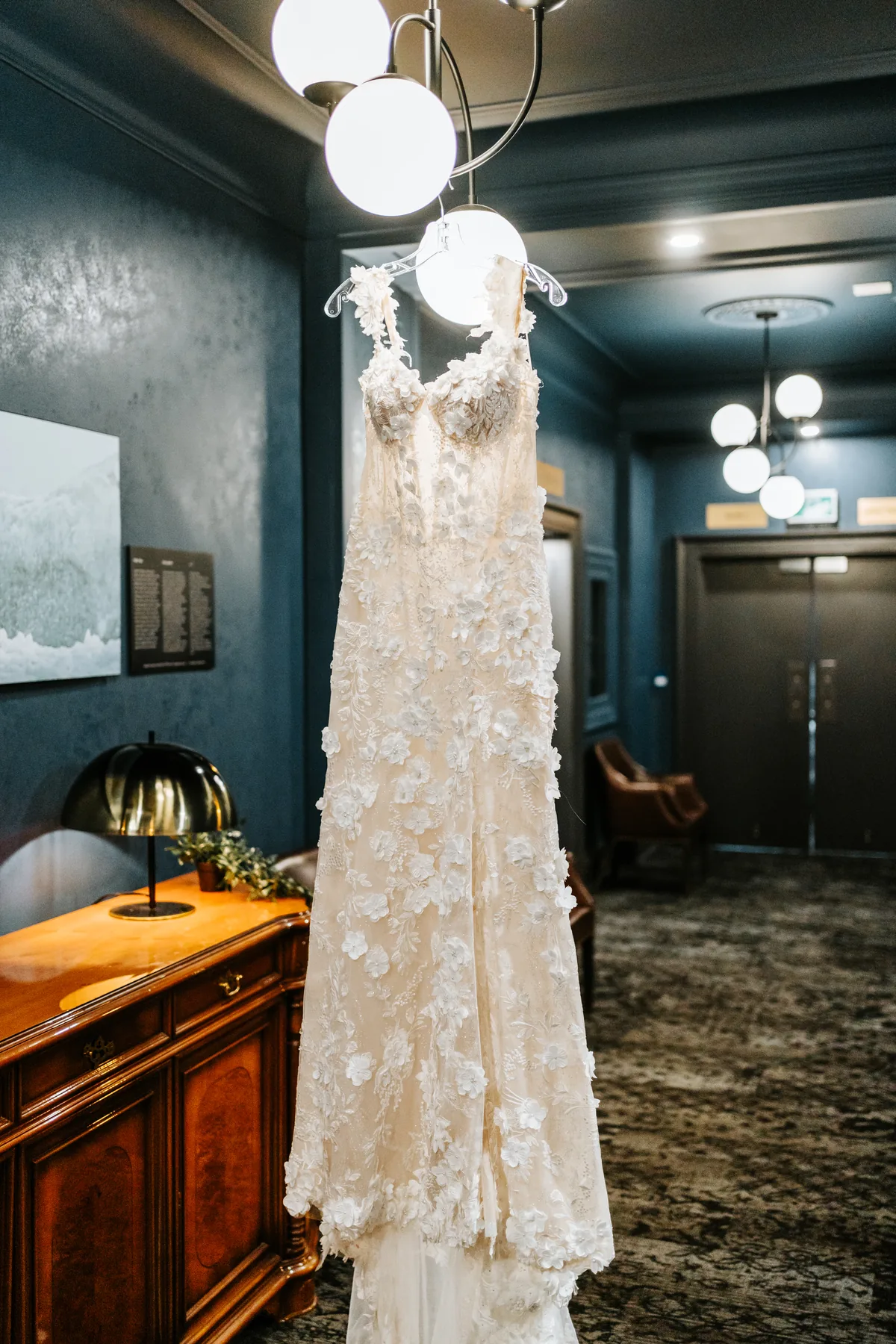 Bride's 3D floral appliqué gown and cathedral veil hanging in the Fort Garry Hotel bridal suite, Winnipeg