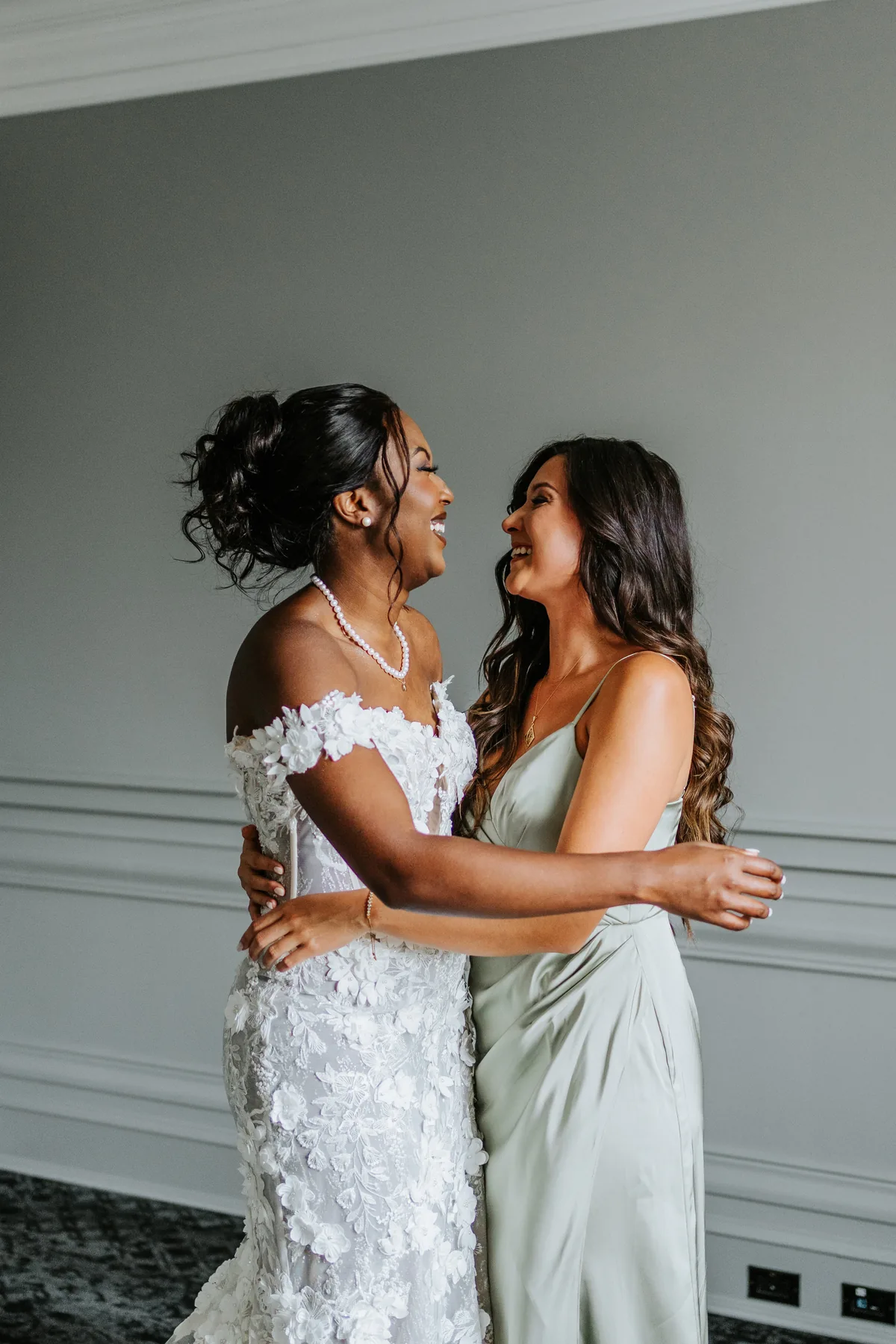 Bride and bridesmaid laughing together before the Fort Garry Hotel wedding ceremony, Winnipeg
