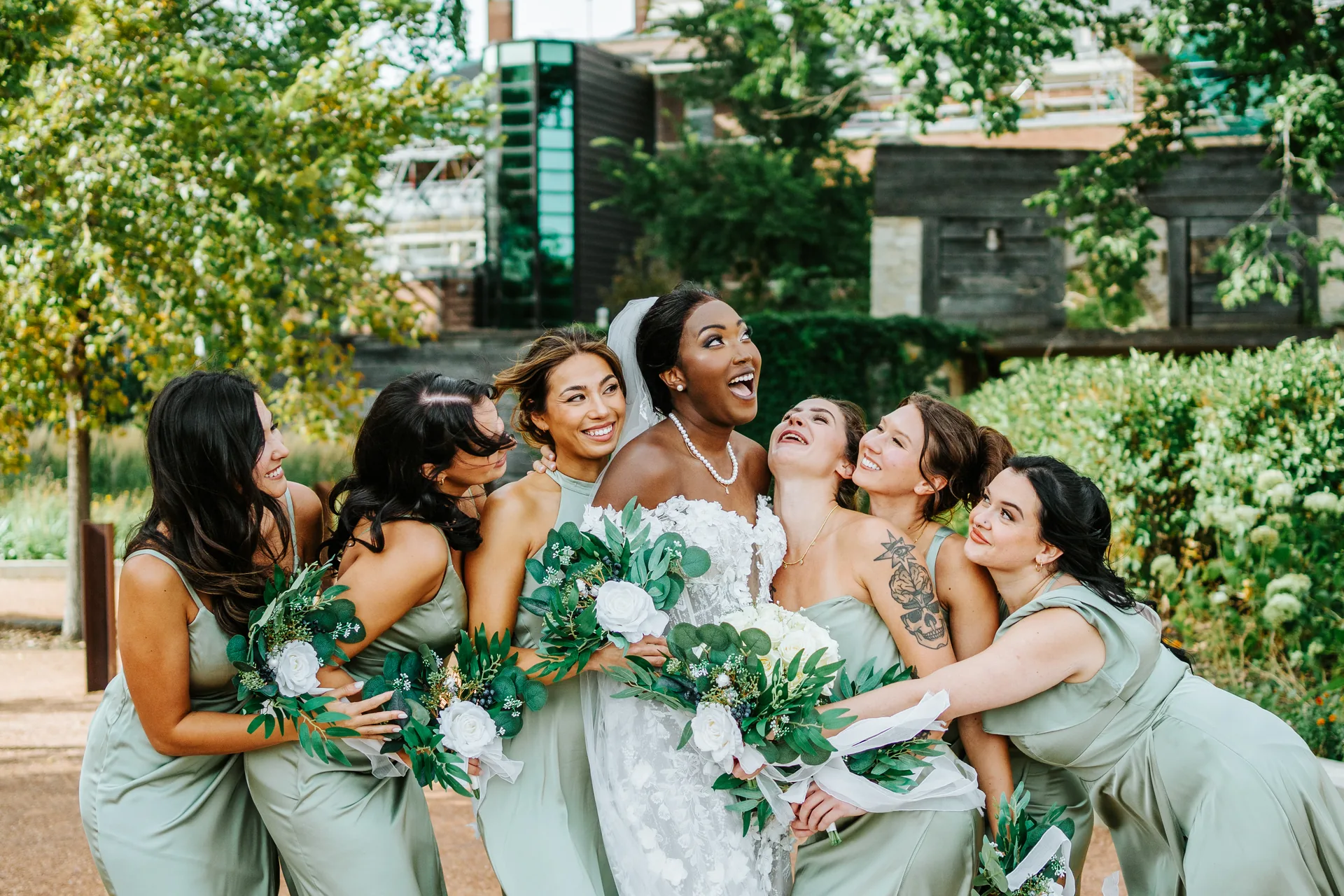 Bridesmaids in sage green satin dresses portrait outdoors at The Forks, Winnipeg