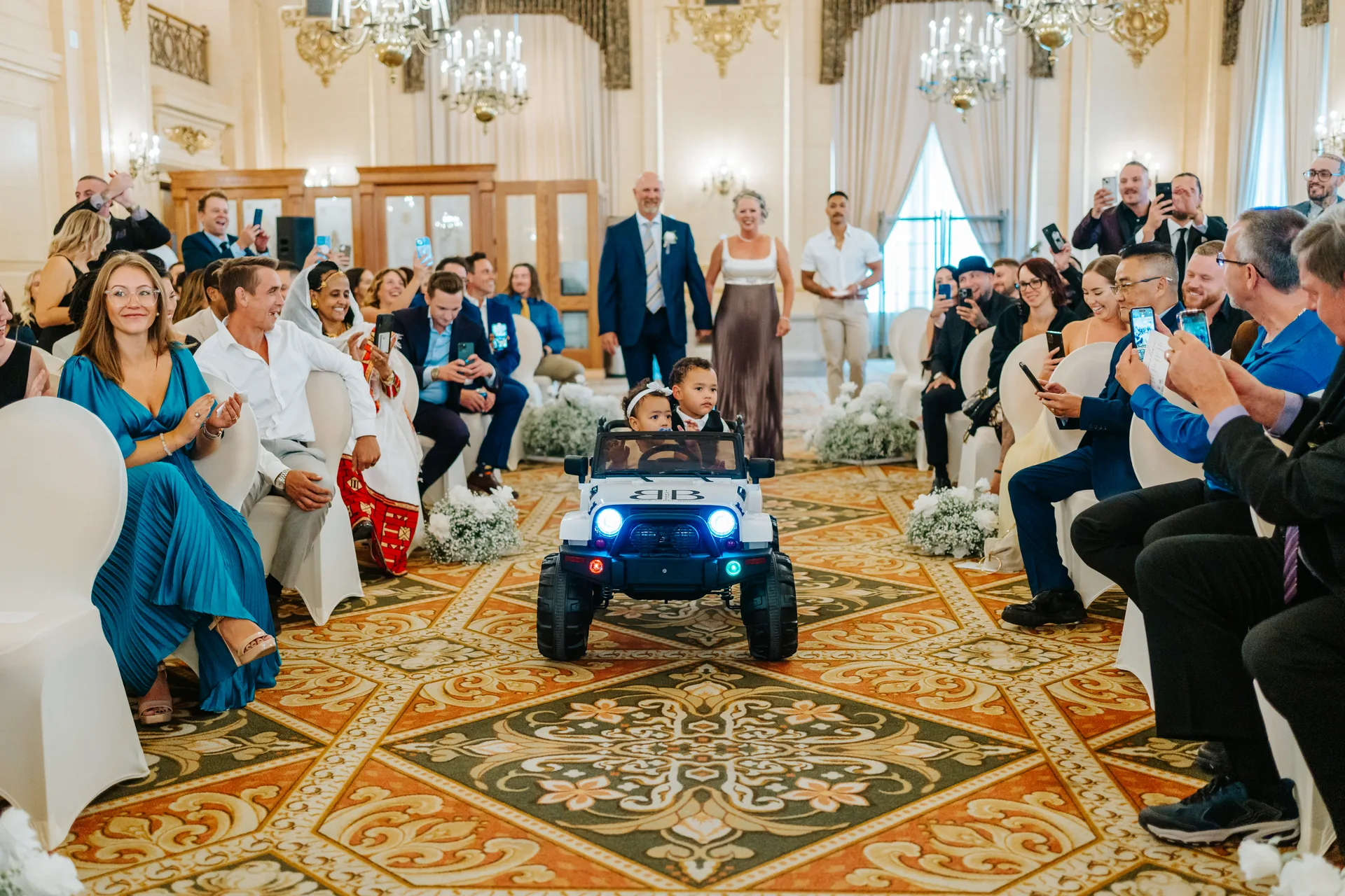 Flower girl driving a white mini power wheels Jeep down the aisle at the Fort Garry Hotel Provencher Ballroom, Winnipeg