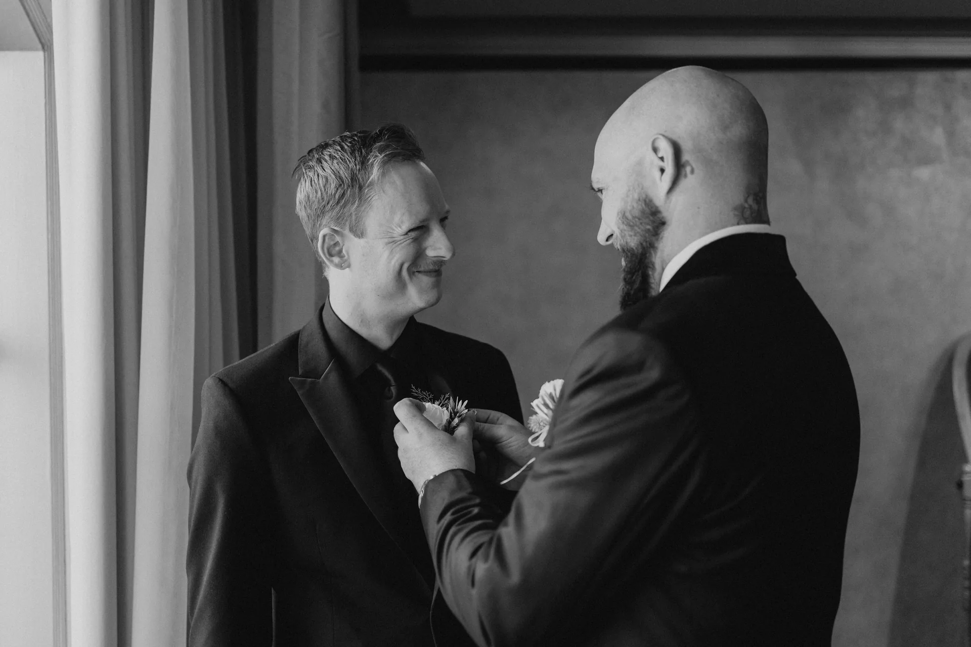 Groomsman pinning the white boutonniere on the groom at the Fort Garry Hotel, Winnipeg