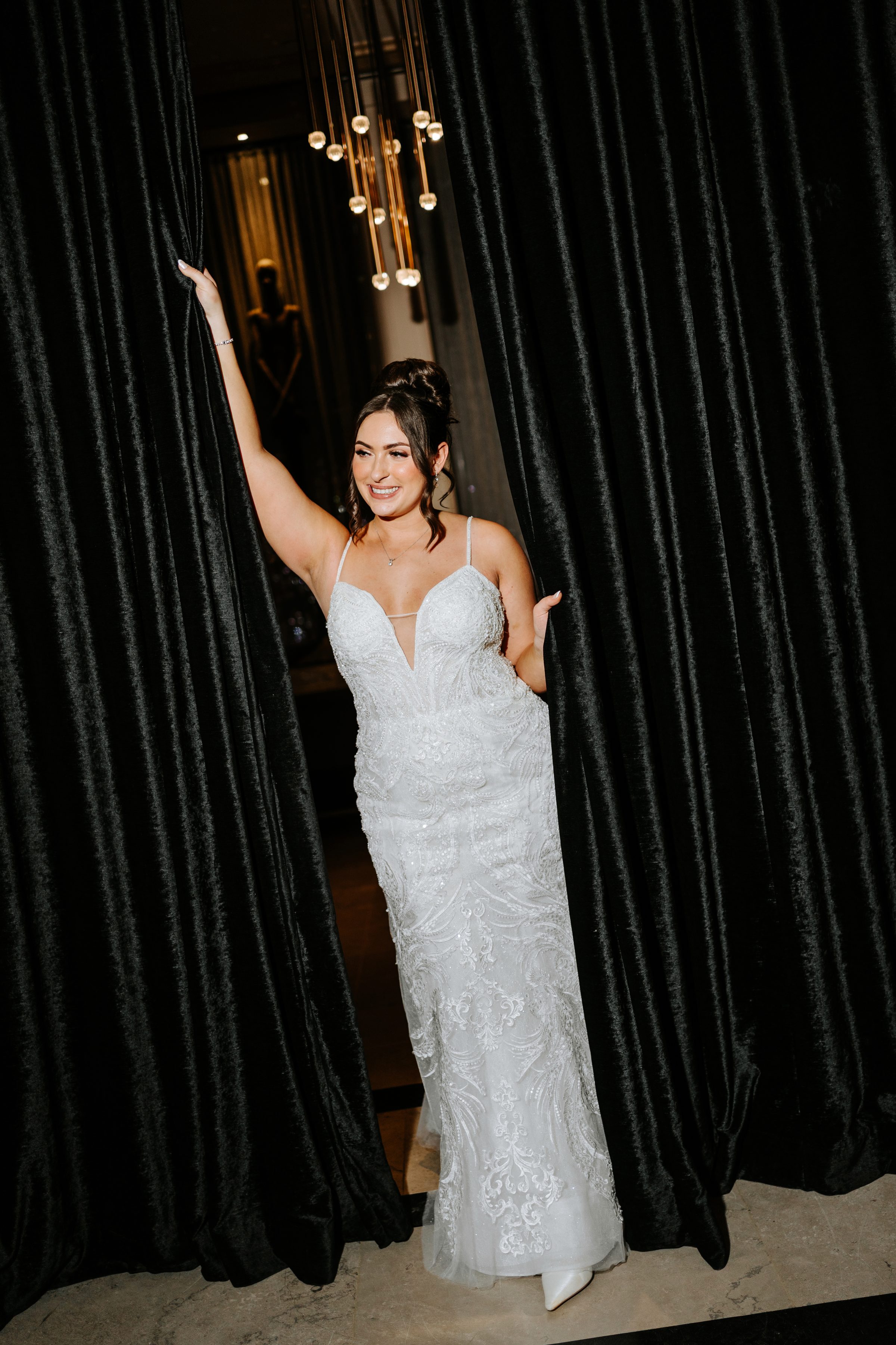 Stef in her wedding dress between velvet curtains at the reception venue — editorial wedding photography by Chris Ngo Winnipeg