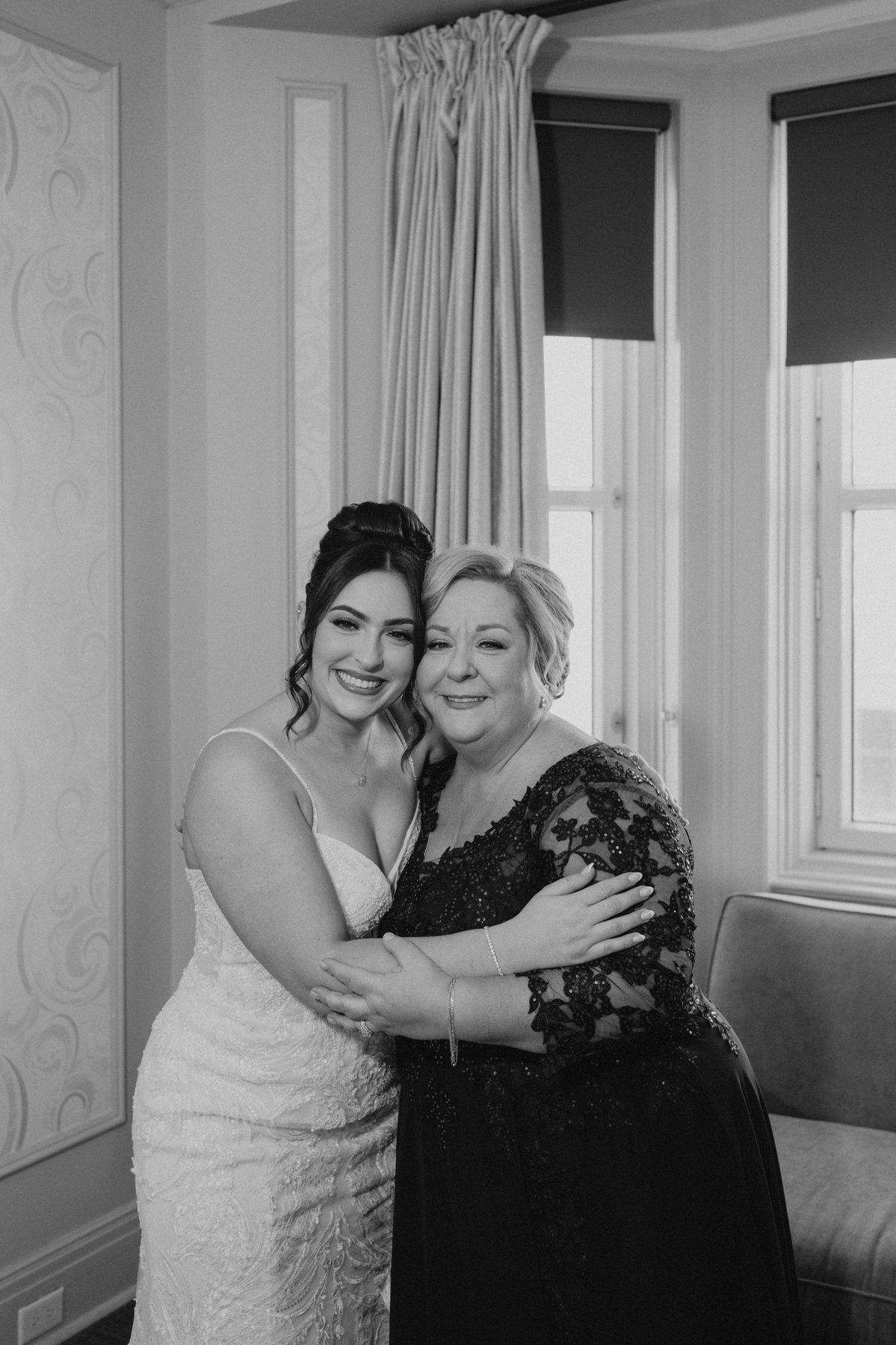 Bride and mother sharing an emotional hug during the first look at The Fort Garry Hotel Winnipeg — candid wedding photography by Ngo Photography
