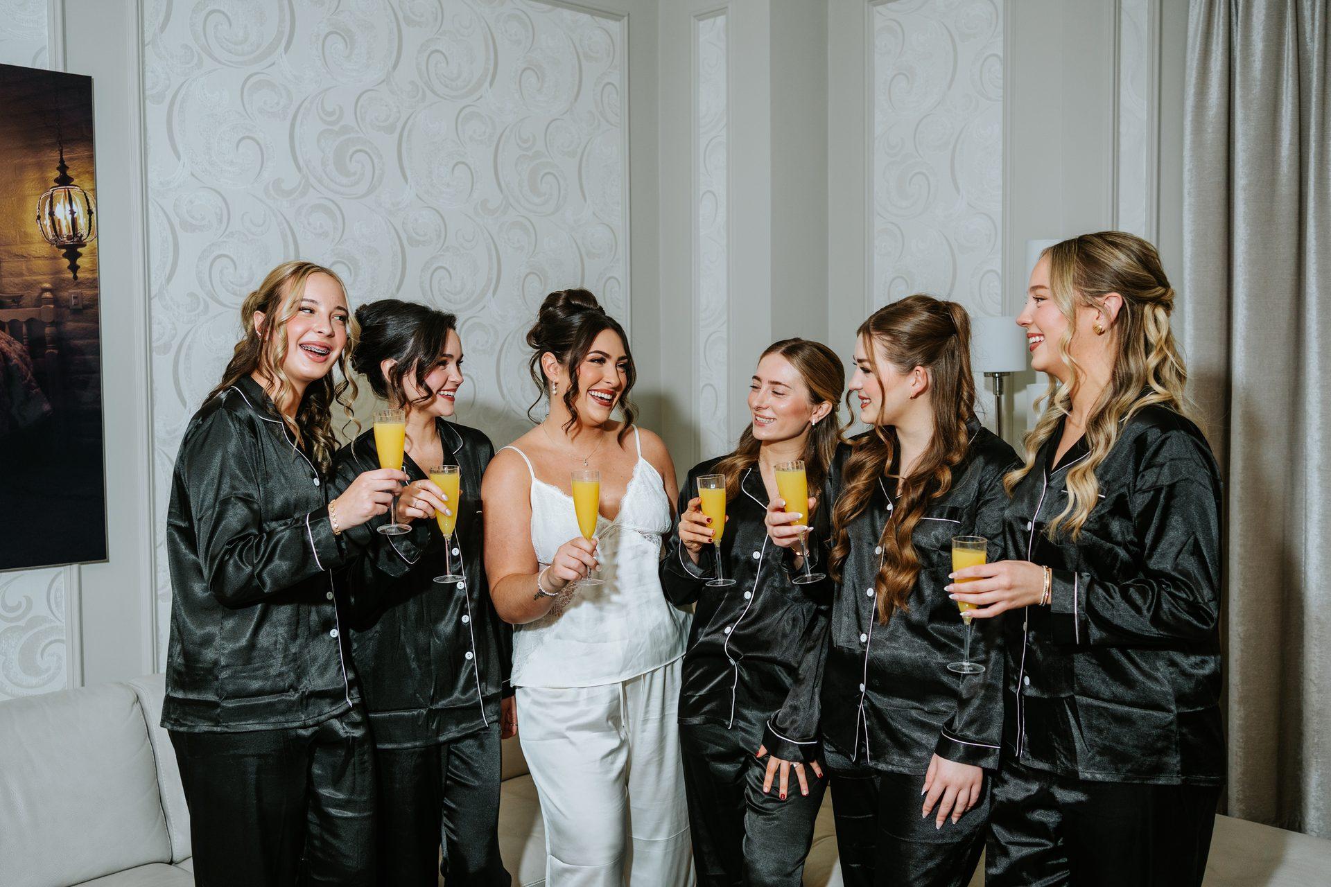 Bridesmaids in matching black pyjamas with mimosas on the morning of the wedding at The Fort Garry Hotel Winnipeg — Ngo Photography