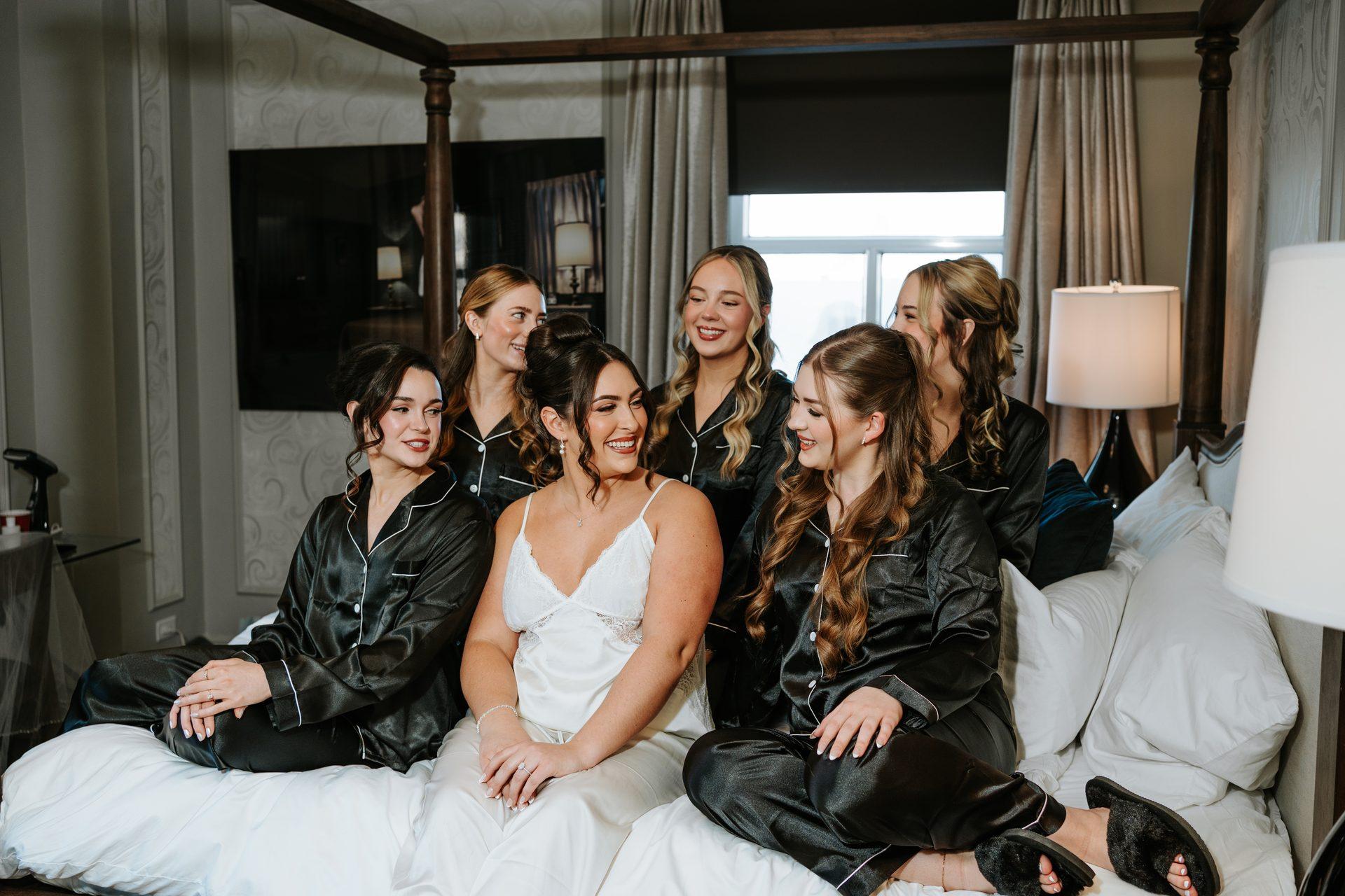 Bride and bridesmaids laughing together on the four-poster bed at The Fort Garry Hotel on the wedding morning — candid photography by Chris Ngo, Ngo Photography Winnipeg