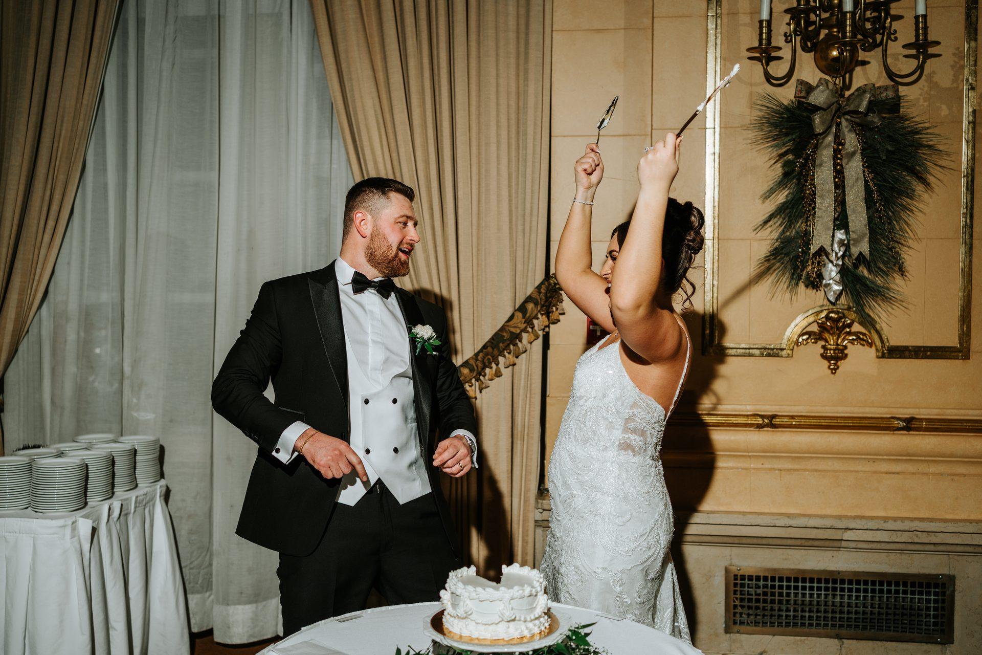 Couple laughing while cutting the wedding cake with a sword at the Fort Garry Hotel, Winnipeg