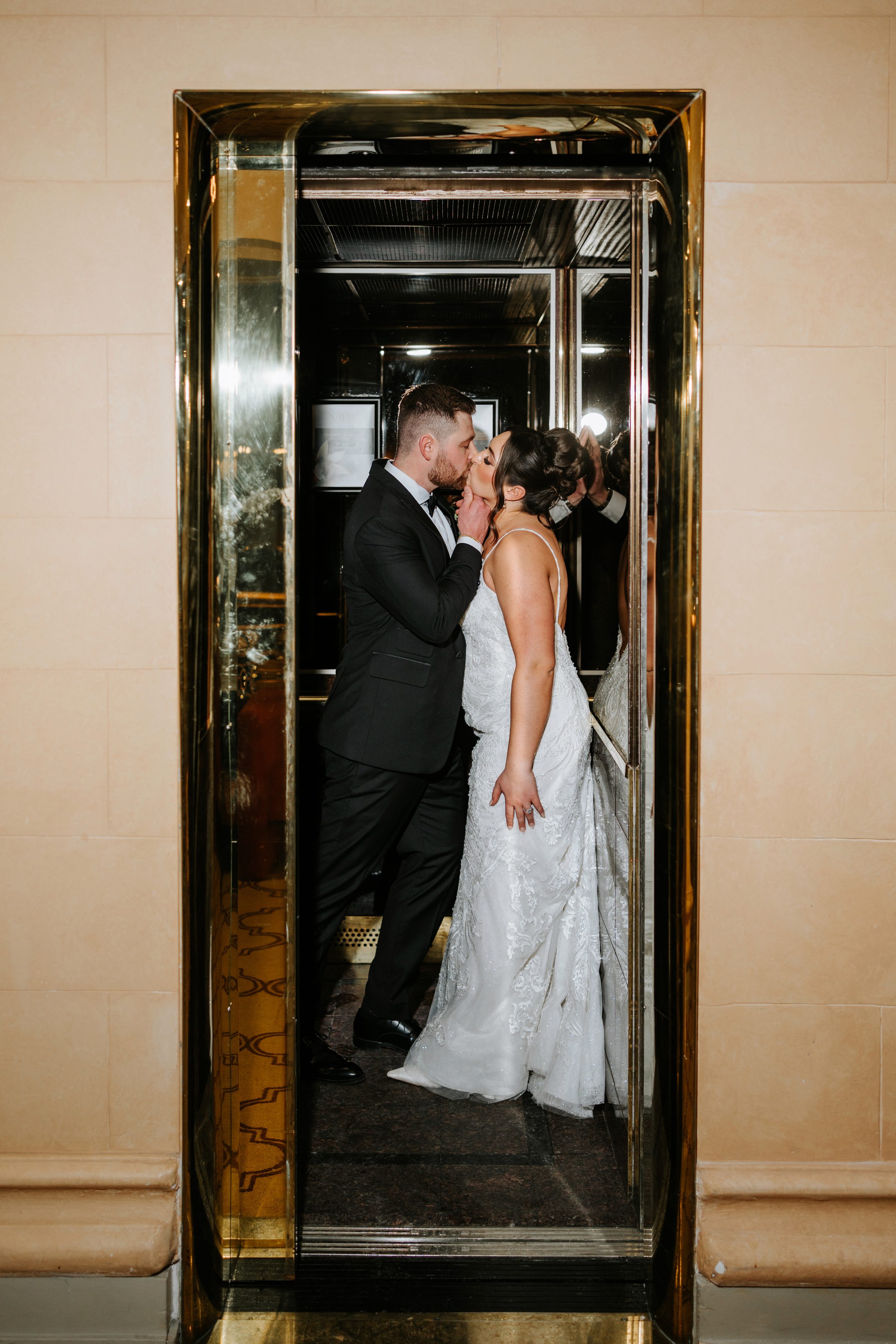 Stef and Brett kissing in a gold elevator at their Winnipeg wedding reception — Ngo Photography
