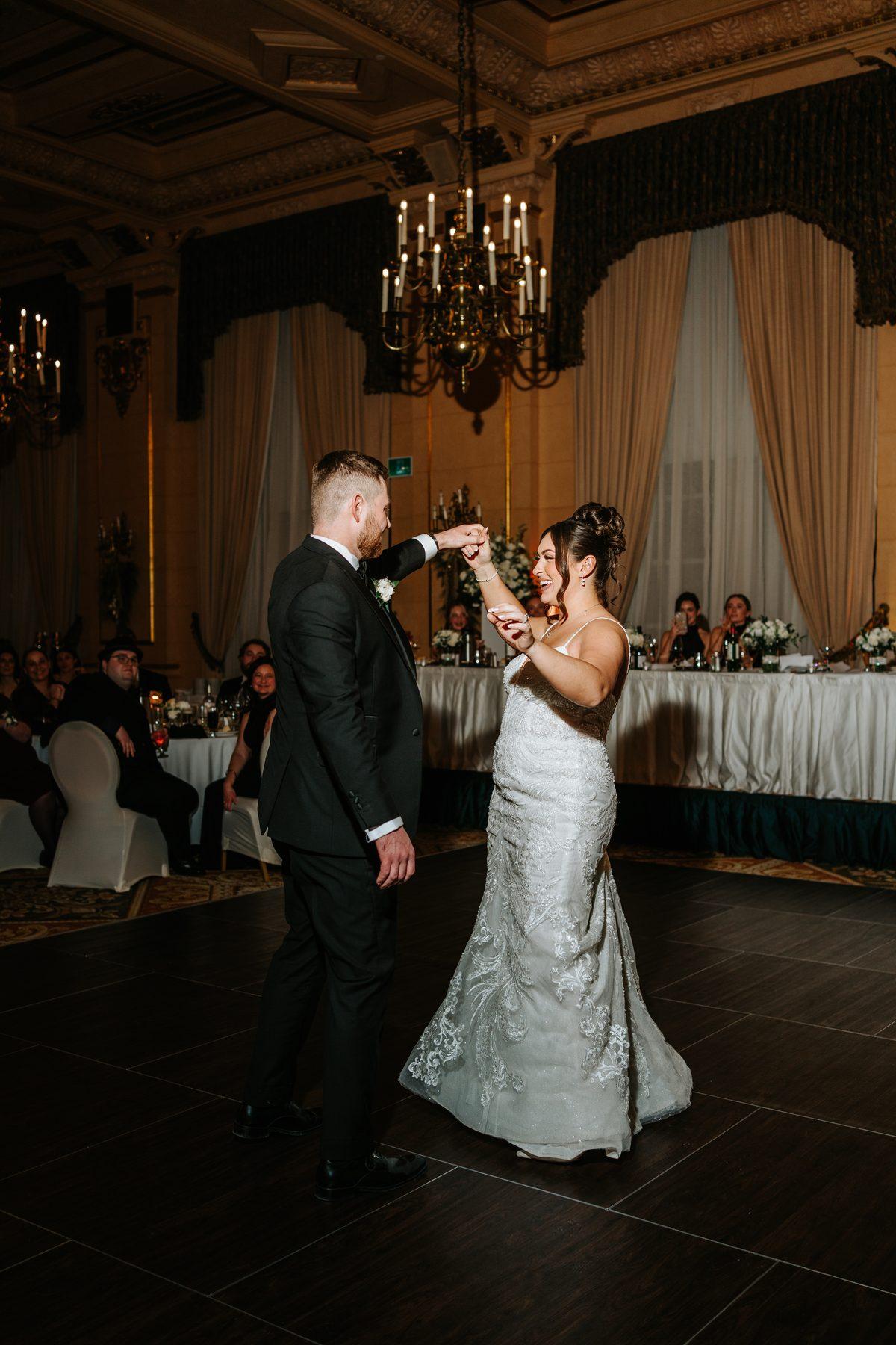 Wide shot of the first dance under the crystal chandeliers of the Provencher Ballroom at The Fort Garry Hotel Winnipeg — wedding photography by Ngo Photography