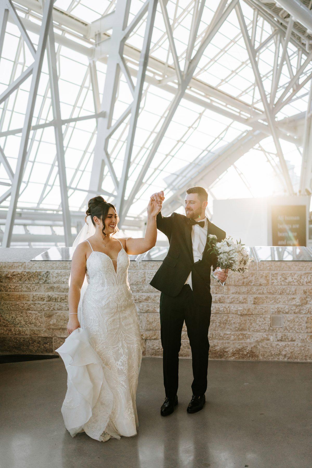 Stef and Brett spinning together in golden light inside the Canadian Museum for Human Rights Winnipeg — wedding portrait by Ngo Photography