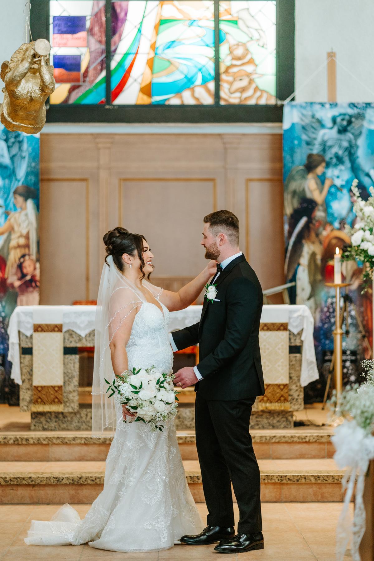 Brett touching Stef's face tenderly at the altar at Holy Rosary Church Winnipeg — intimate wedding ceremony photography by Ngo Photography