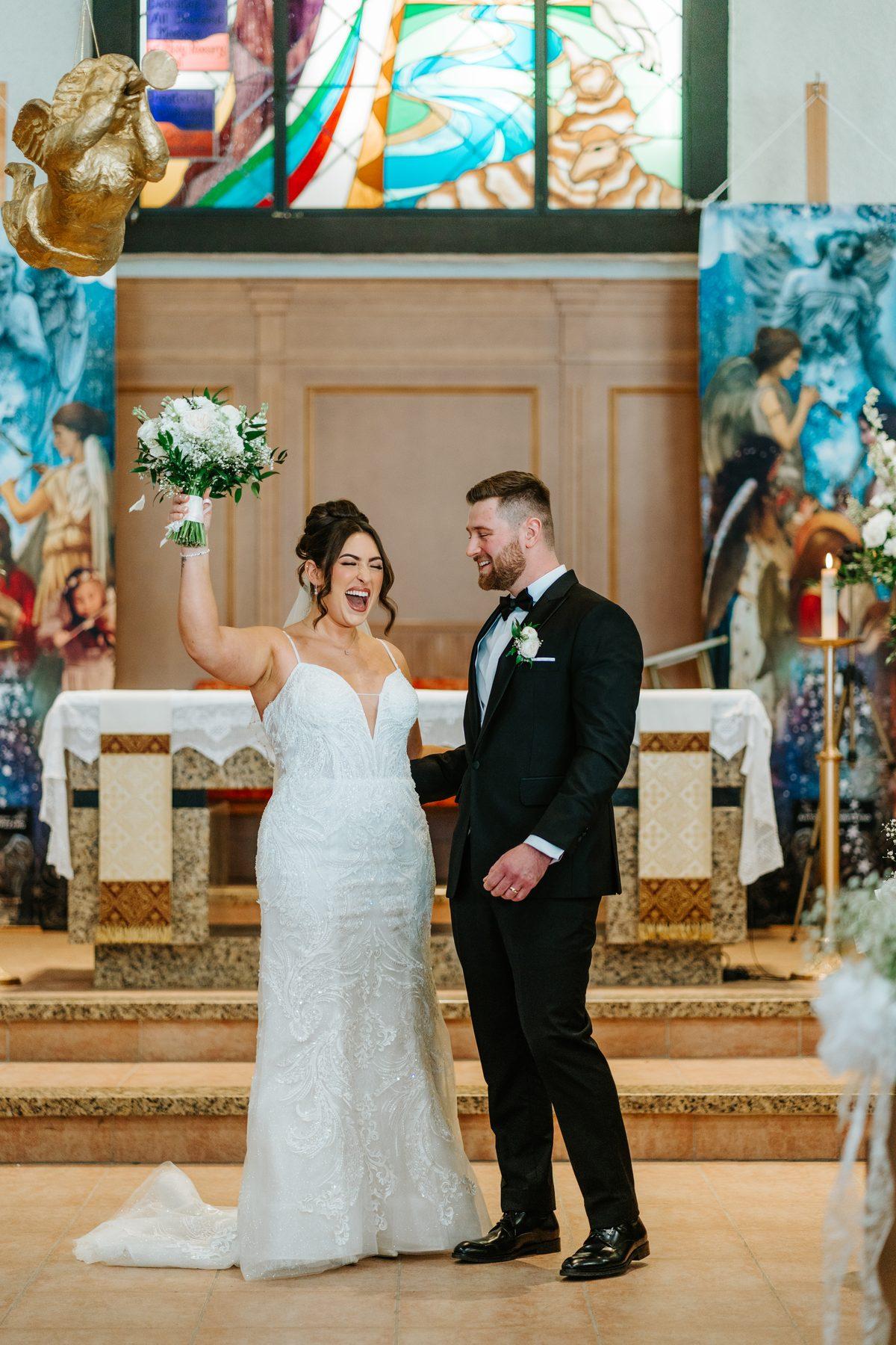 Just married — bride raising her bouquet in celebration at Holy Rosary Church, Winnipeg