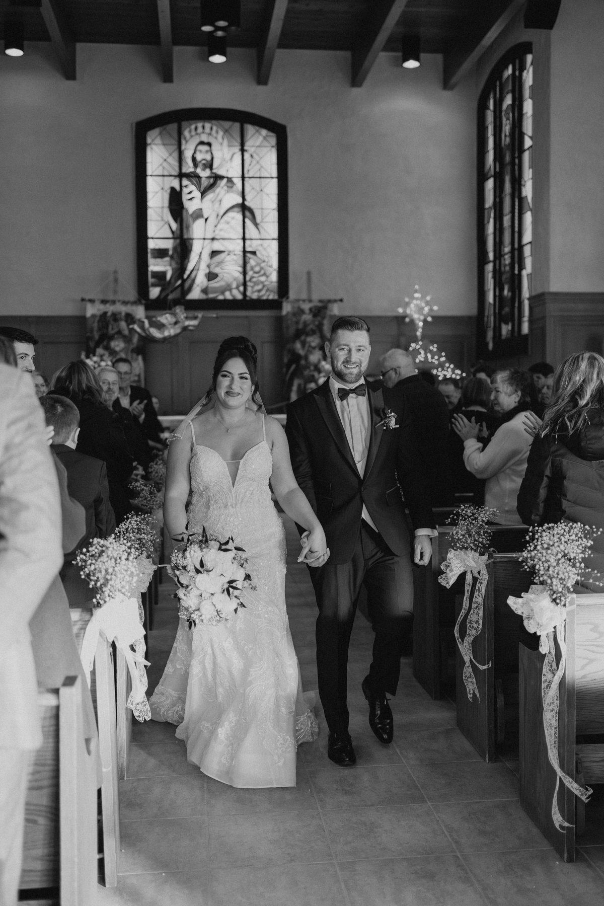 Newlyweds walking the recessional aisle as husband and wife at Holy Rosary Church, Winnipeg