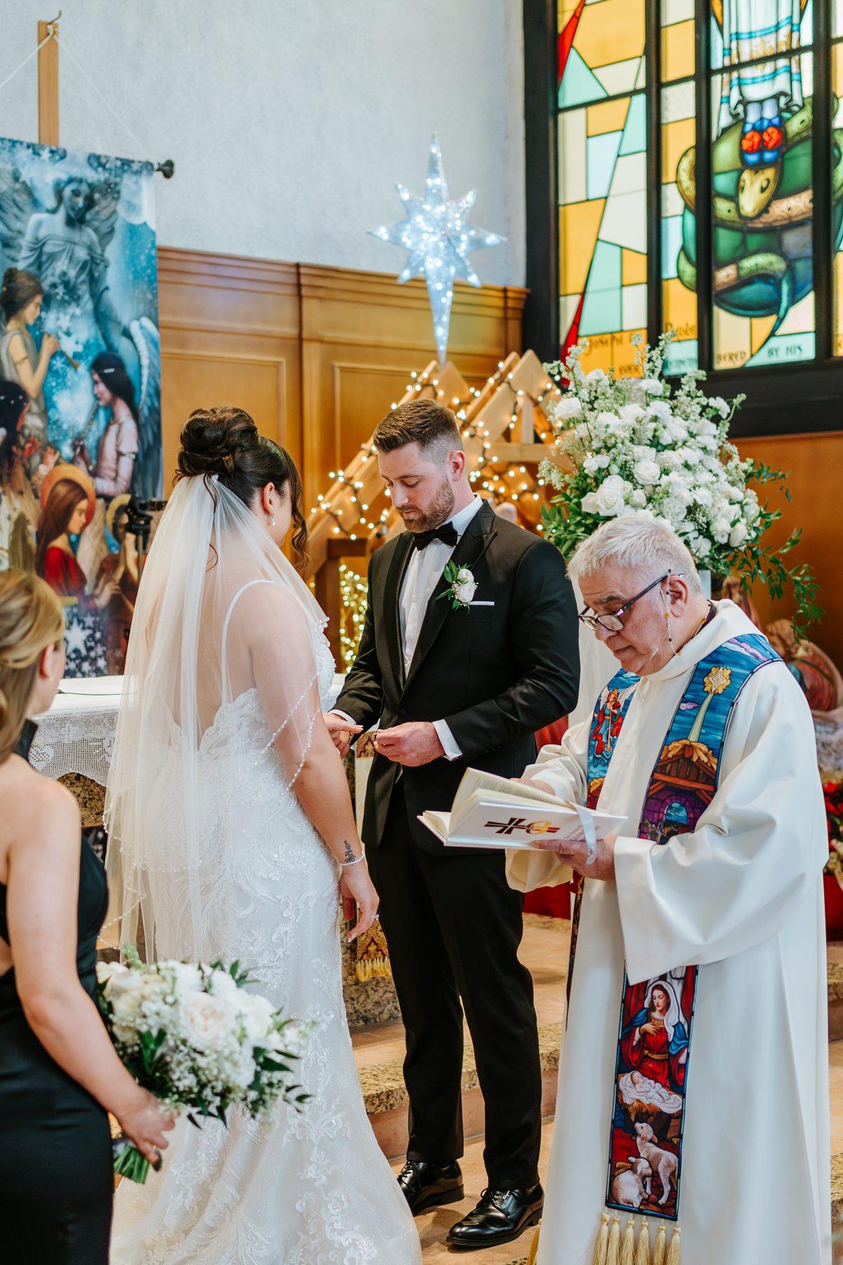 Ring exchange at Holy Rosary Church with stained glass windows in the background, Winnipeg