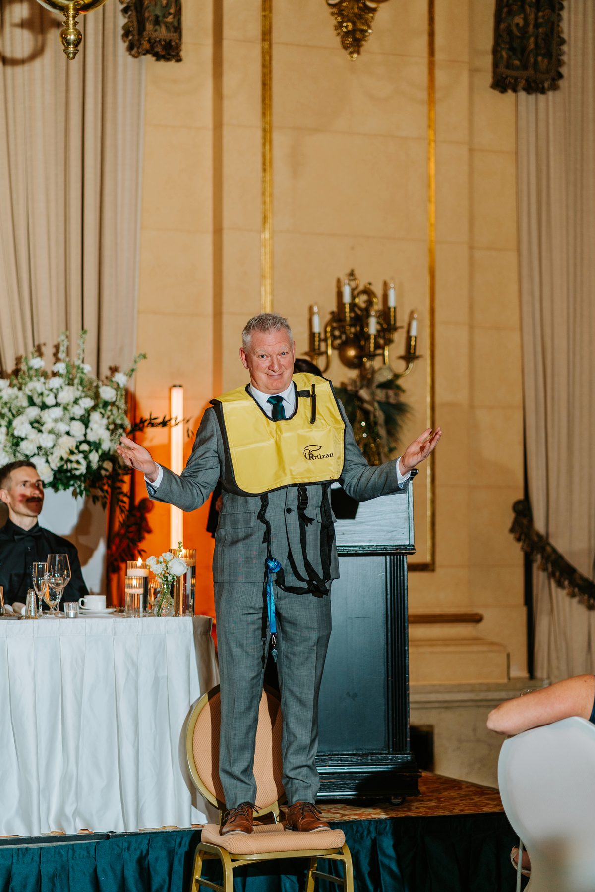 Groomsman giving a wedding speech with a lifejacket at The Fort Garry Hotel reception Winnipeg — candid photography by Ngo Photography