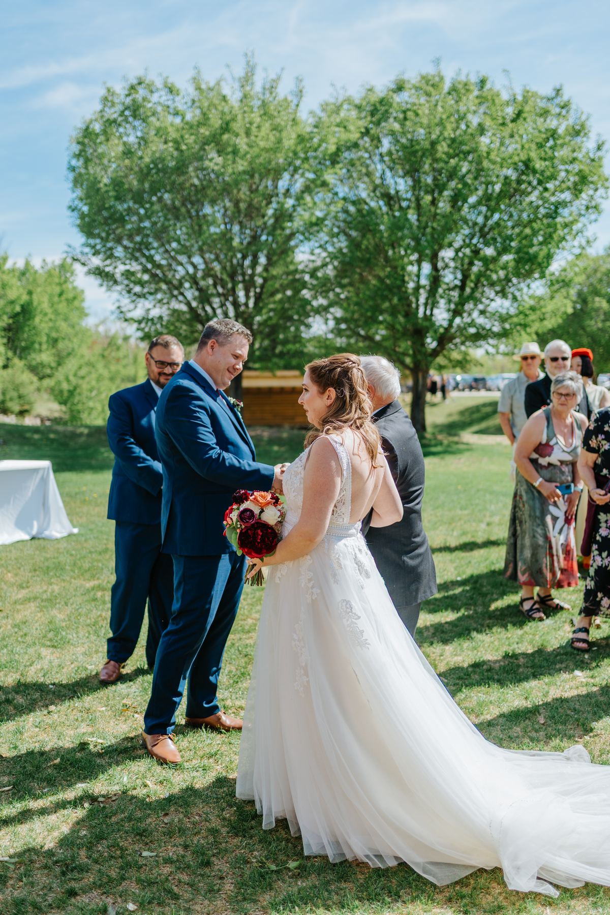 Bride Tara walking the aisle in her white ball gown at the Pineridge Hollow outdoor ceremony, Manitoba