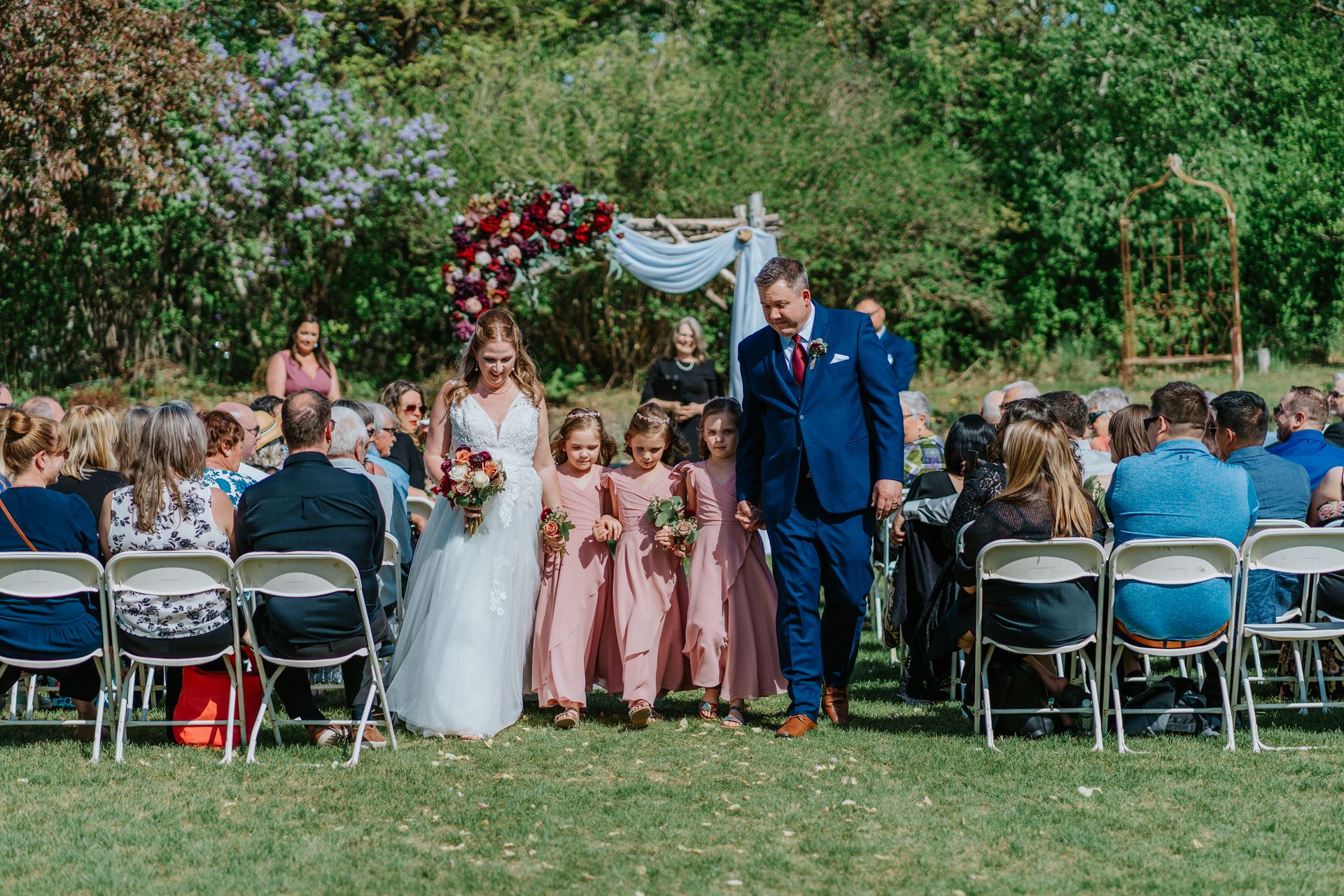 Tara and Carter recessional as just-married couple through the perennial garden at Pineridge Hollow, Winnipeg