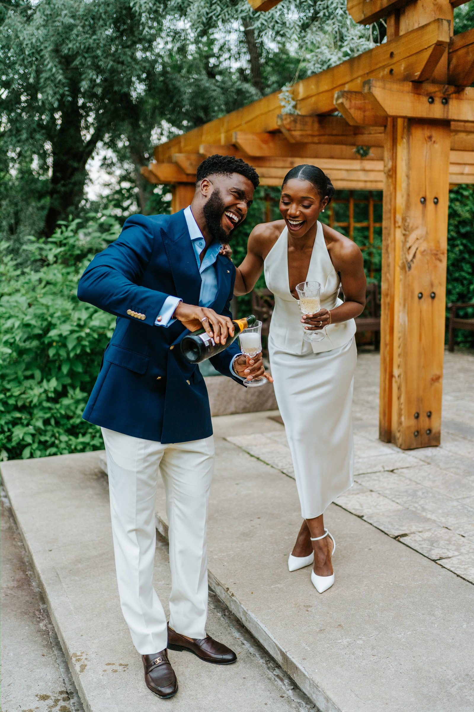 Emeka and Tobi celebrating with champagne at Leo Mol Sculpture Garden — Assiniboine Park, Winnipeg wedding photography