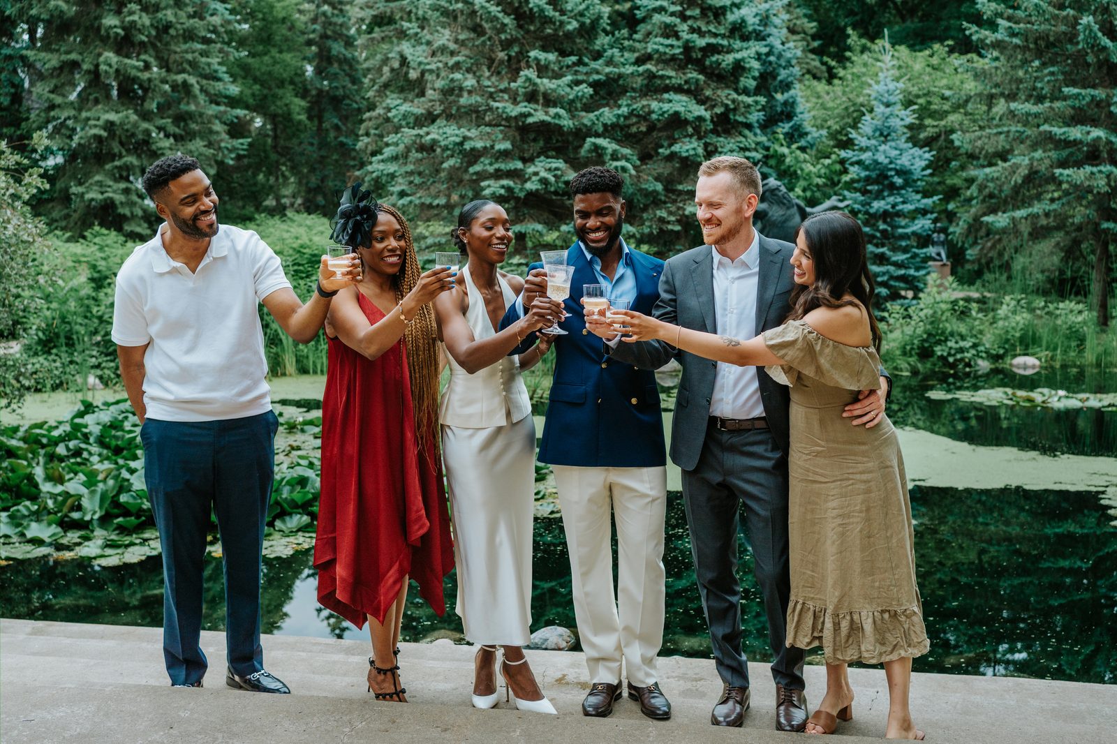 Tobi and Emeka laughing together with champagne at Leo Mol Sculpture Garden in Assiniboine Park, Winnipeg — post-ceremony celebration